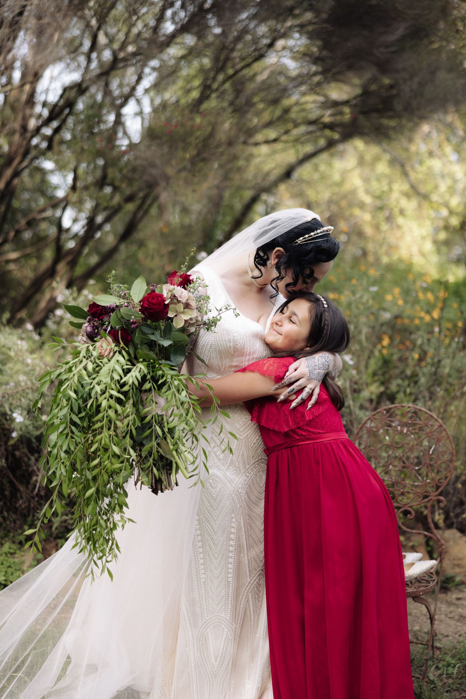Emotional wedding party moment captured with bride and bridesmaids in burgundy velvet.