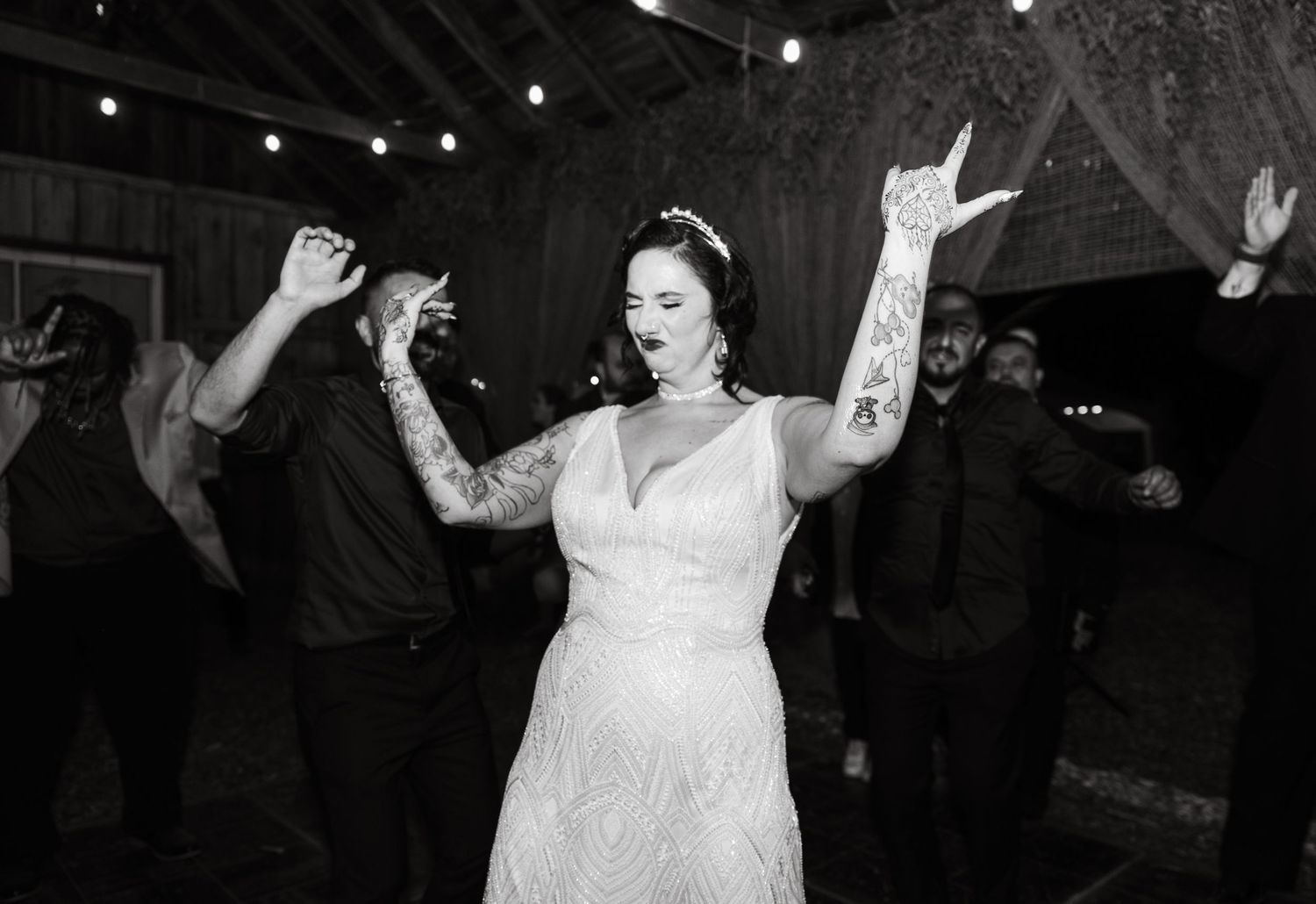 Black and white photo of joyful dancing at a rustic barn wedding reception.