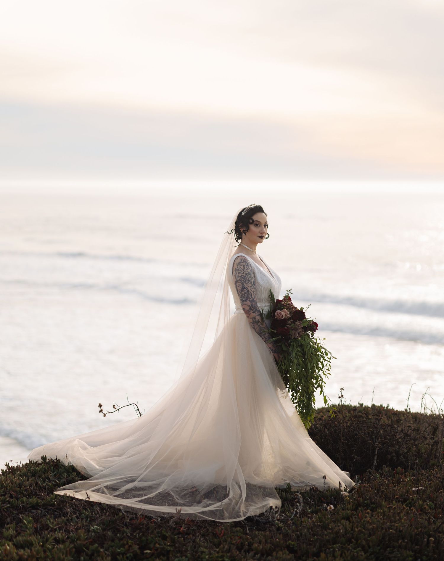 Ethereal bridal portraits against a misty ocean backdrop at sunset.