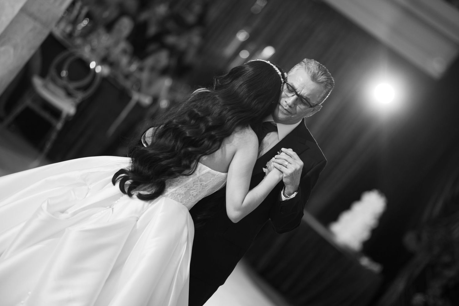 Black and white photo of a bride and groom sharing their first dance at a wedding reception.