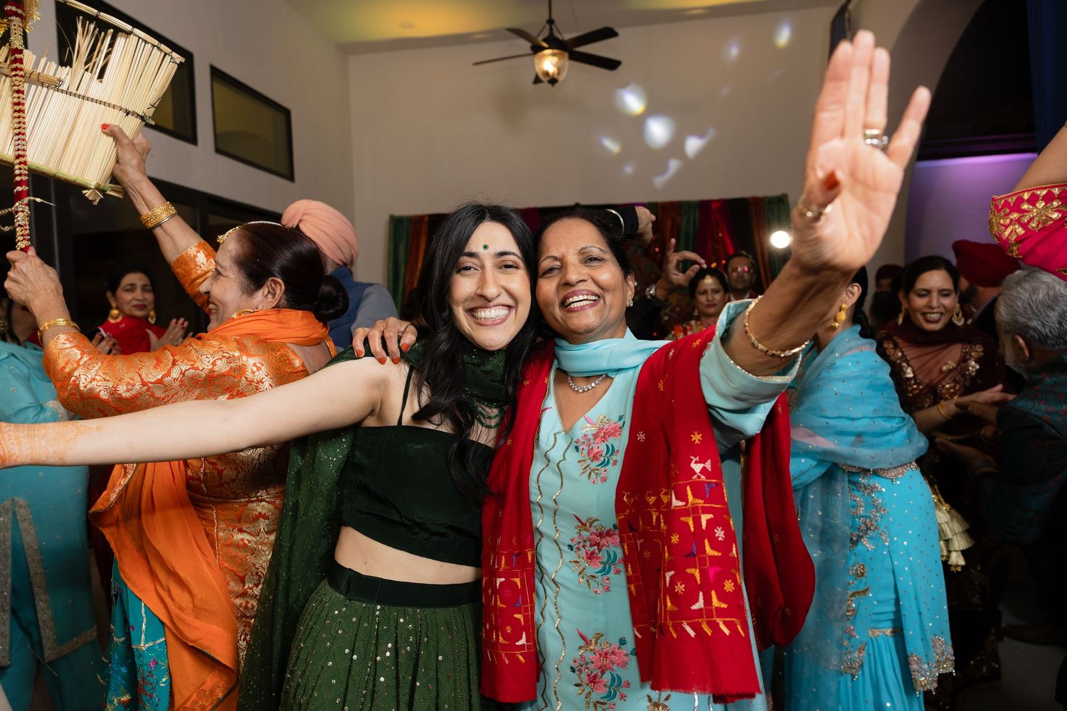 Celebratory dance scene with people wearing colorful traditional Indian and Pakistani attire.