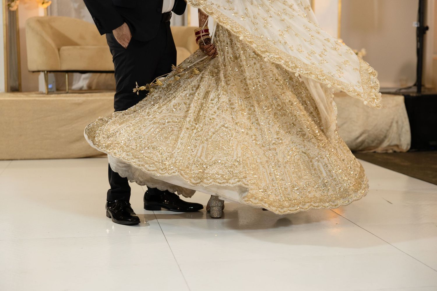 A bridal gown with a flowing champagne-colored skirt twirls elegantly during a fashion show or photoshoot.