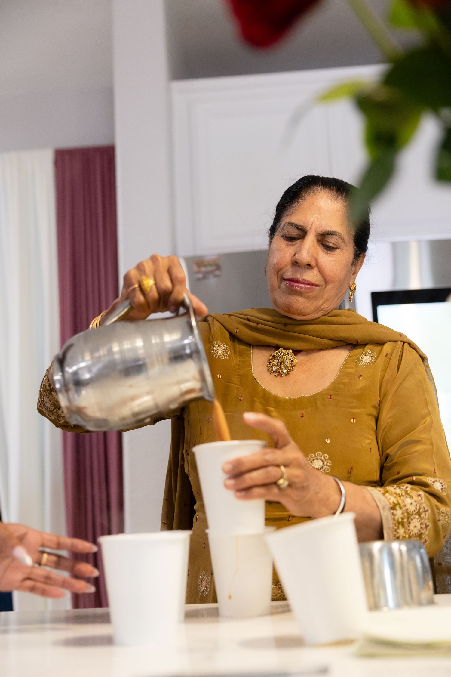 A sequence of photos showing someone pouring and mixing drinks in glasses on a white table.