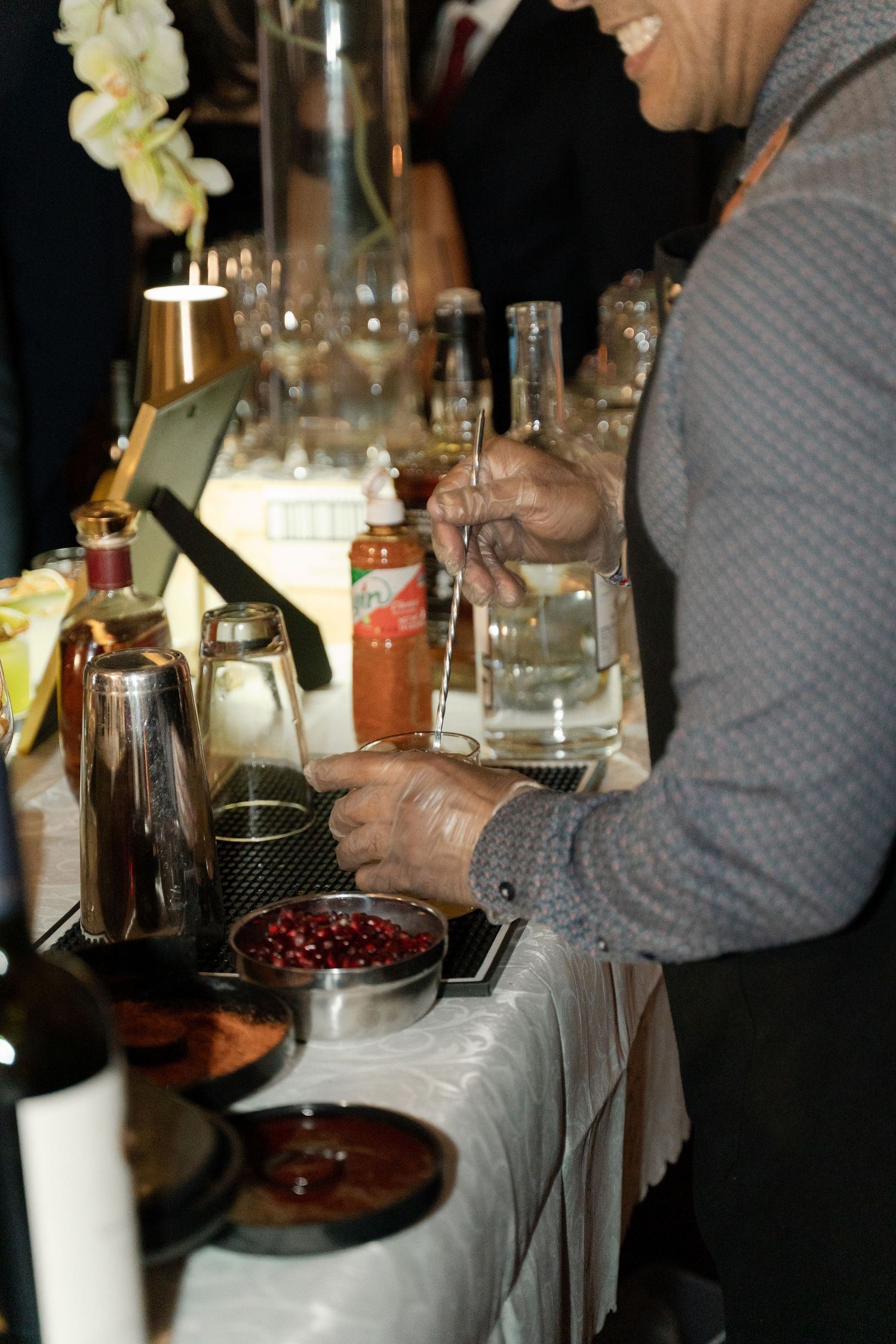 Professional mixologist crafting specialty drinks with various ingredients at a bar station.