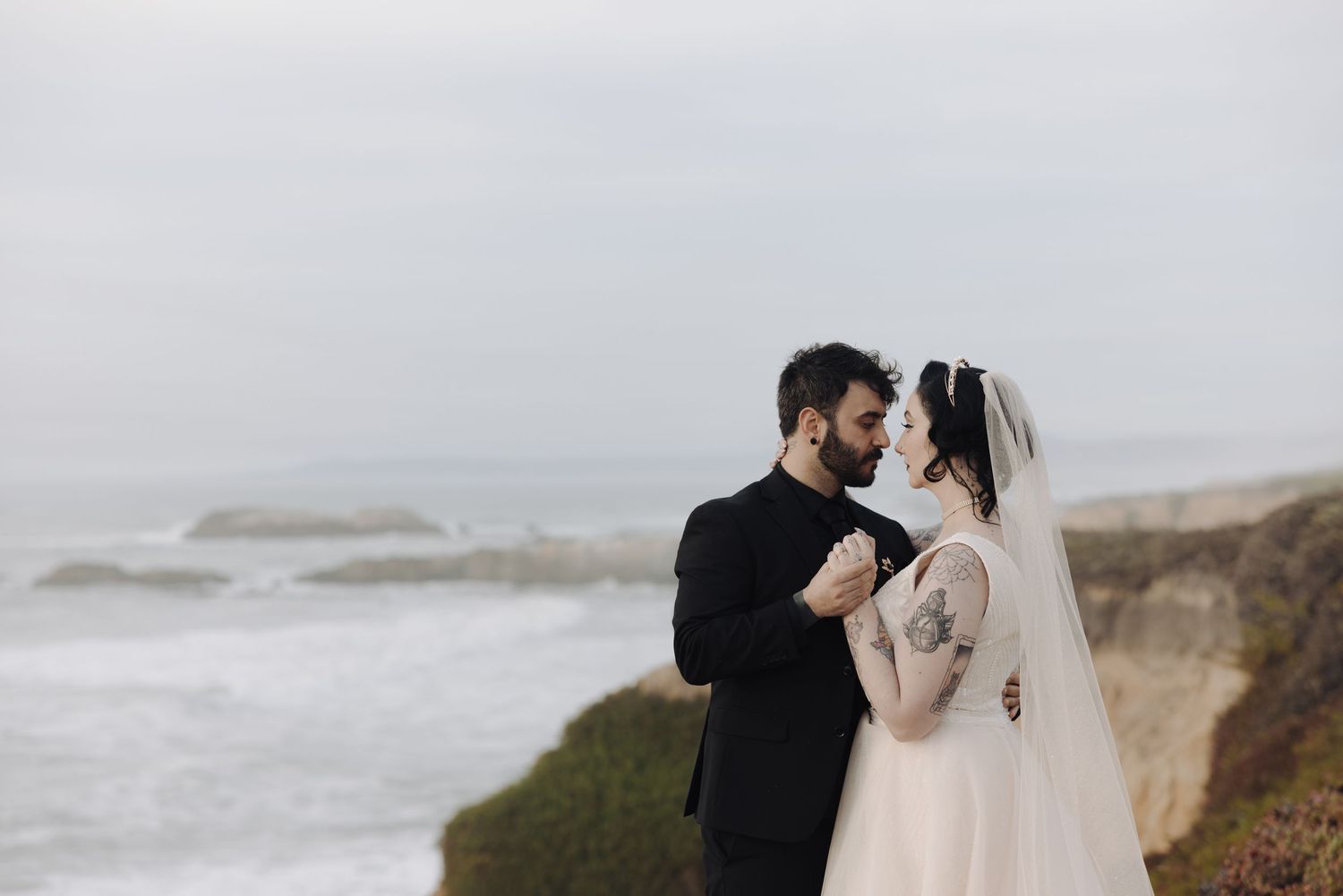 Romantic coastal wedding scene with dramatic cliffs and ocean backdrop.