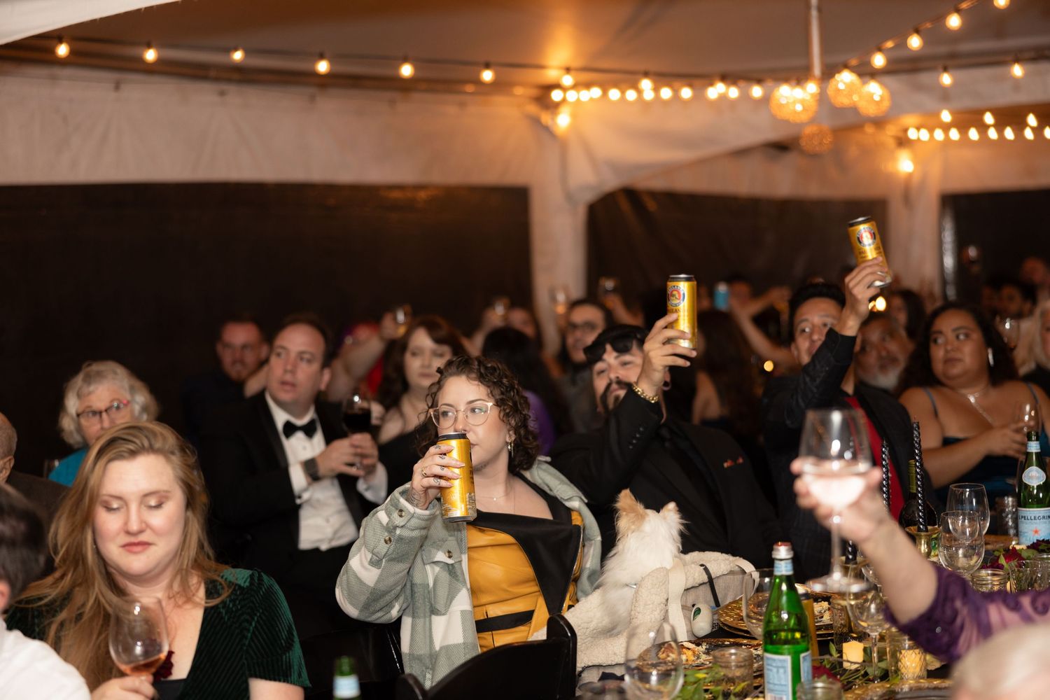 Festive wedding reception scene with string lights and guests enjoying dinner at long tables.