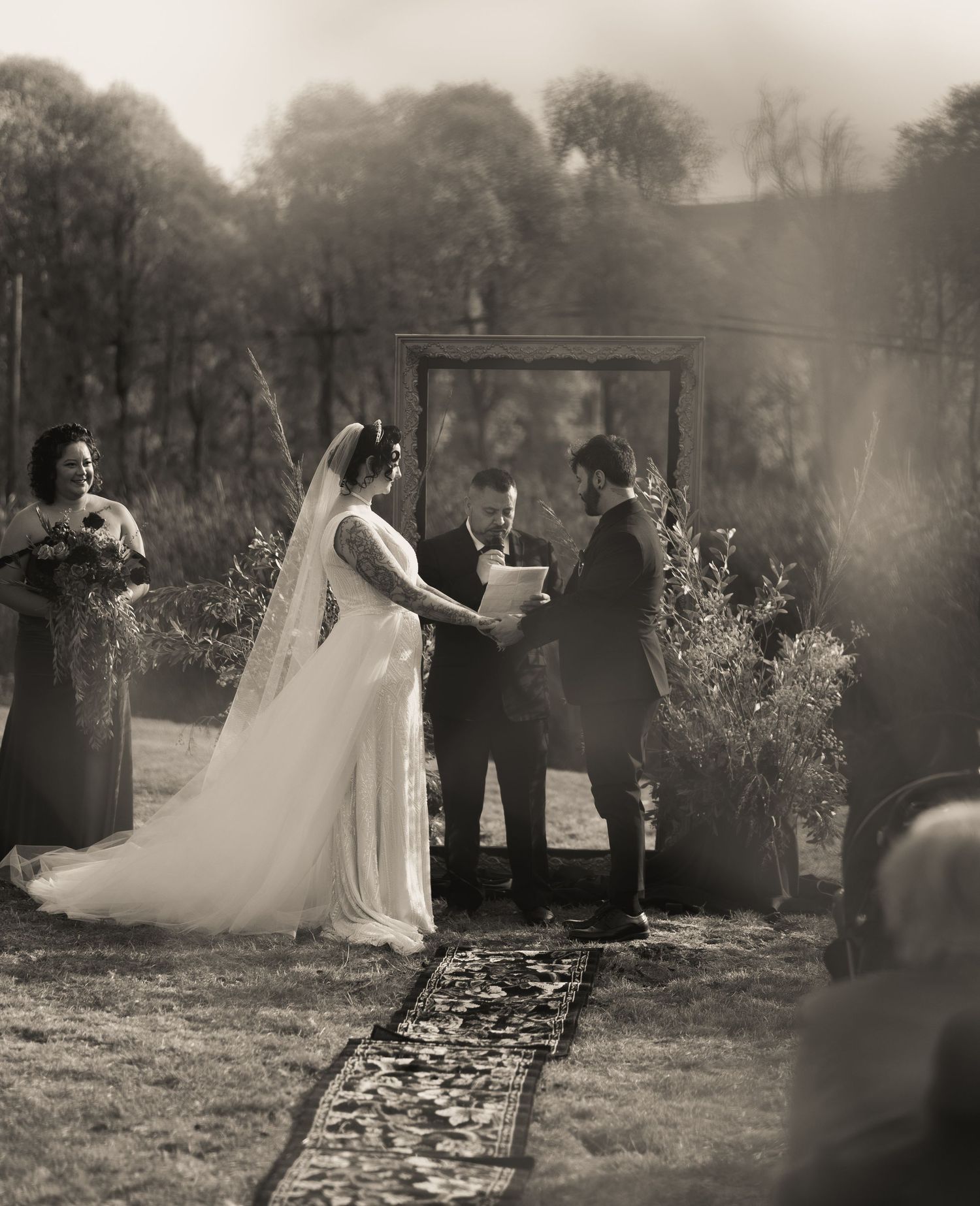 Black and white photo of a wedding ceremony with guests gathered around an outdoor altar.