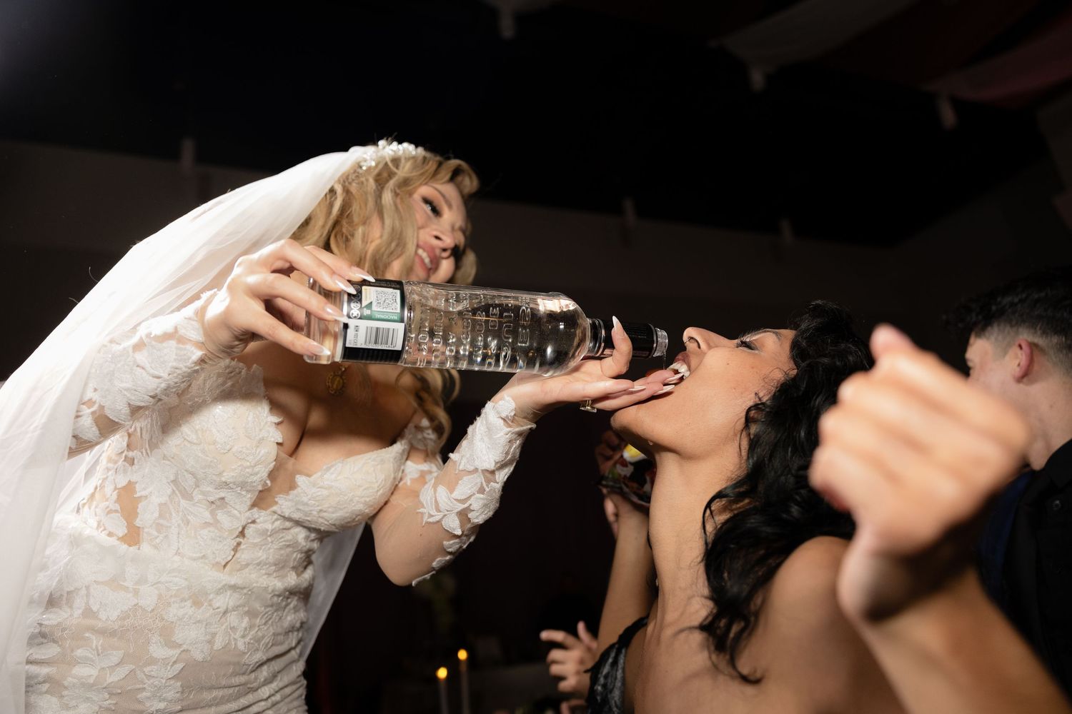 A bride pours drinks for wedding guests during reception celebrations.