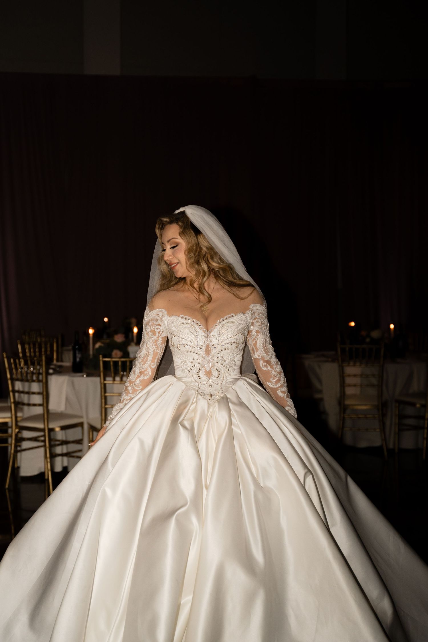 A dramatic bridal portrait series showing a luxurious ball gown wedding dress in dark lighting.