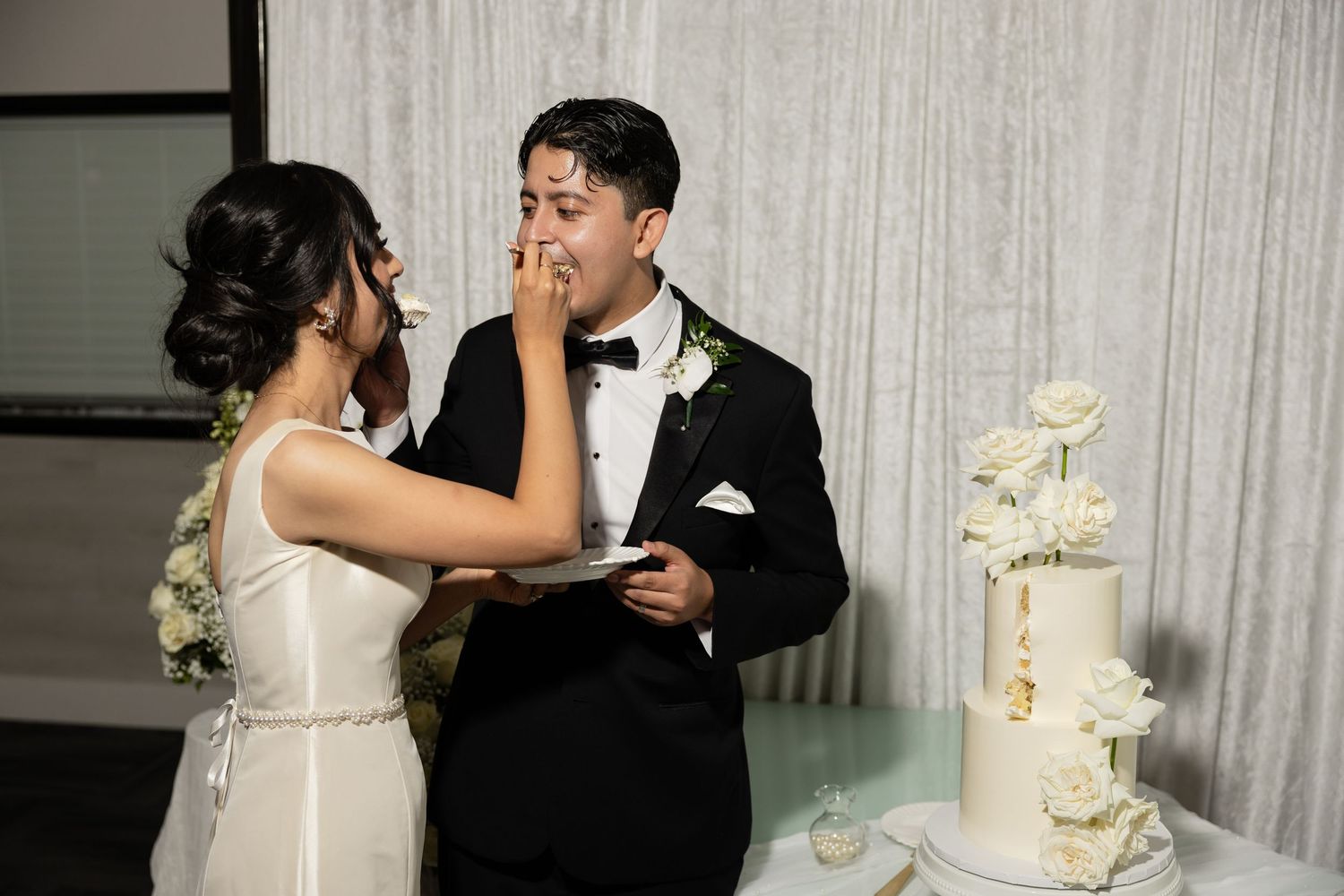 A couple shares their first bite of wedding cake during their reception celebration.