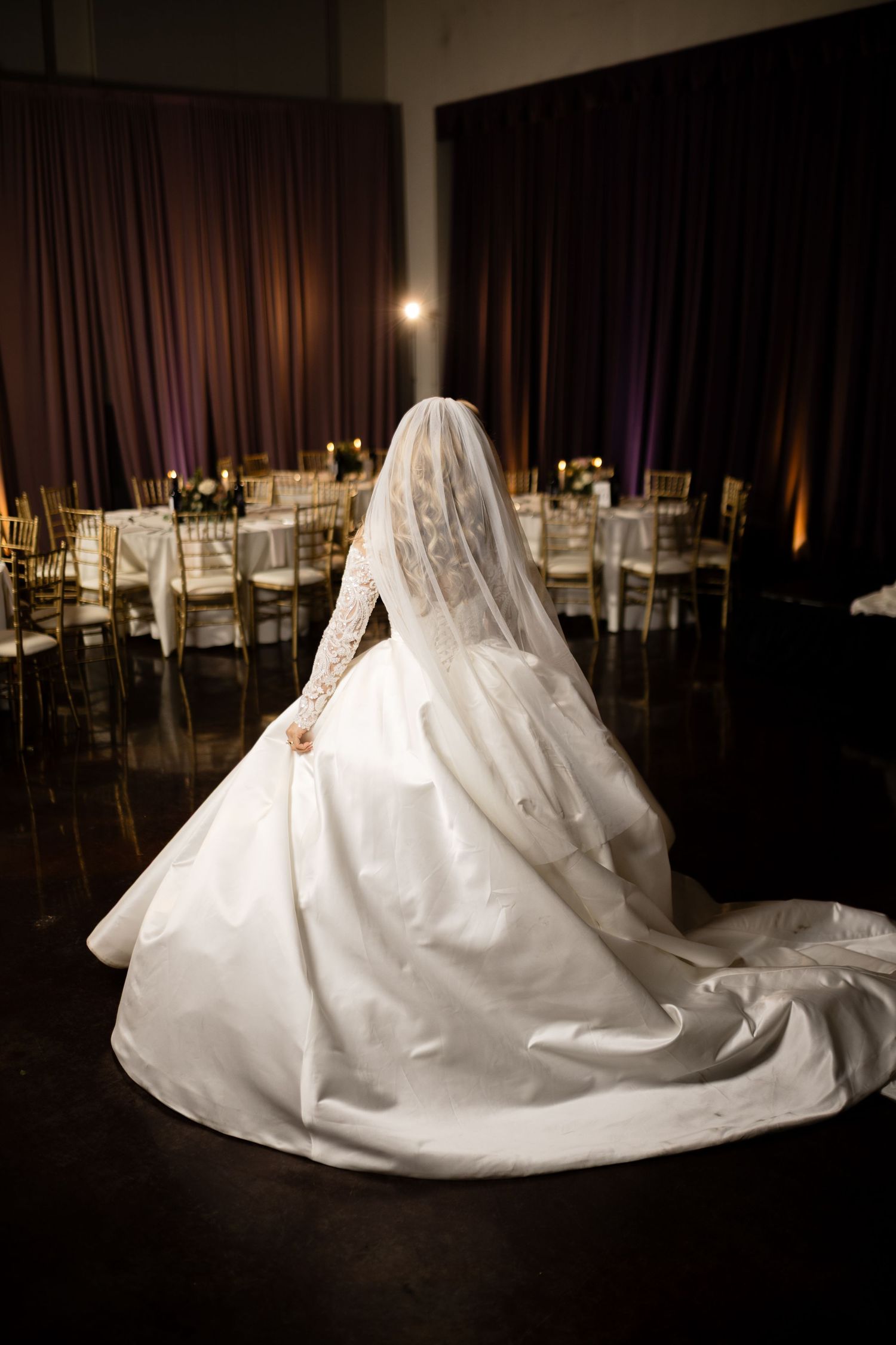 A back view of a wedding dress with cathedral train in an elegant reception venue.