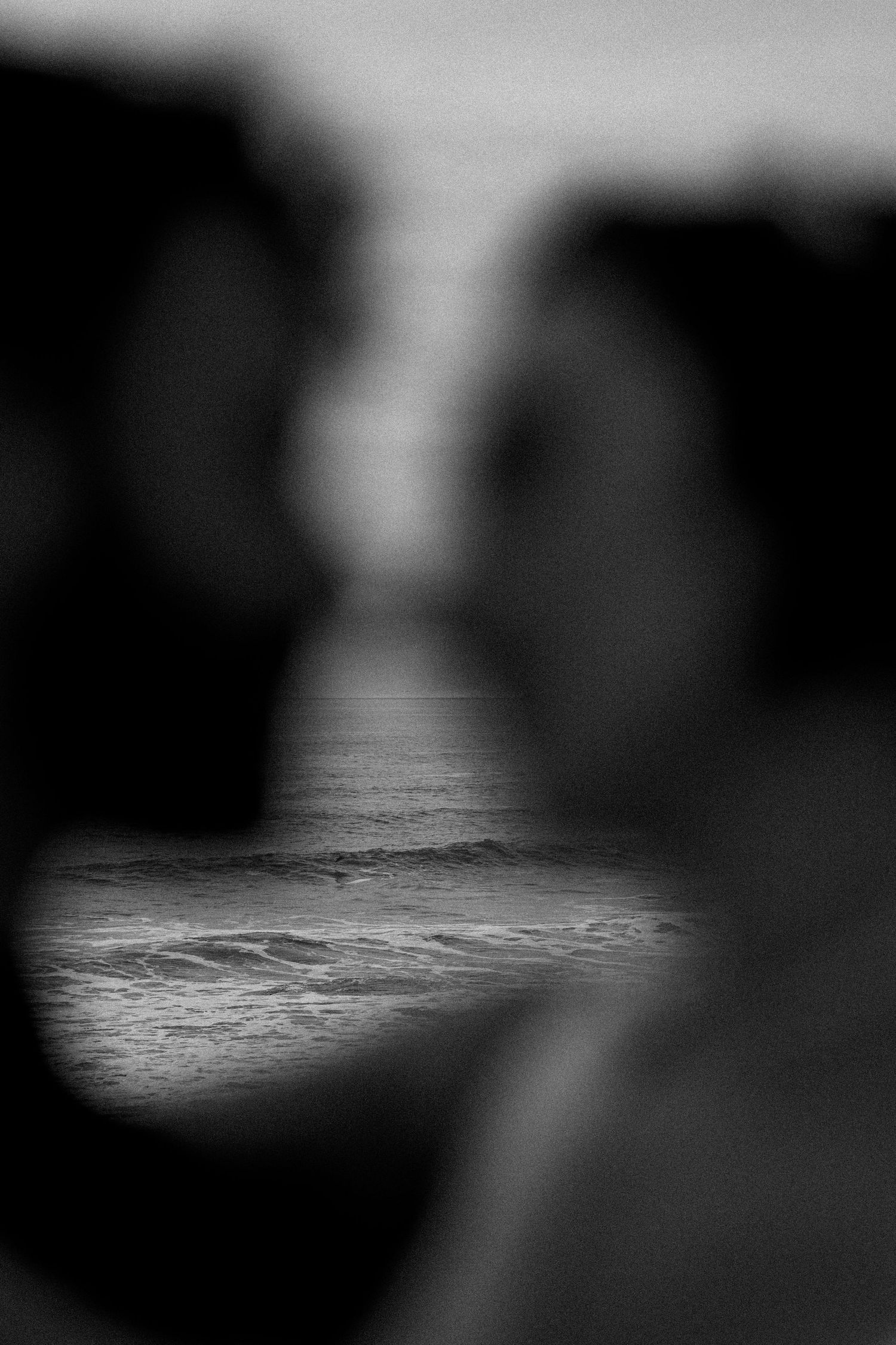 Abstract black and white ocean waves with blurred foreground elements.