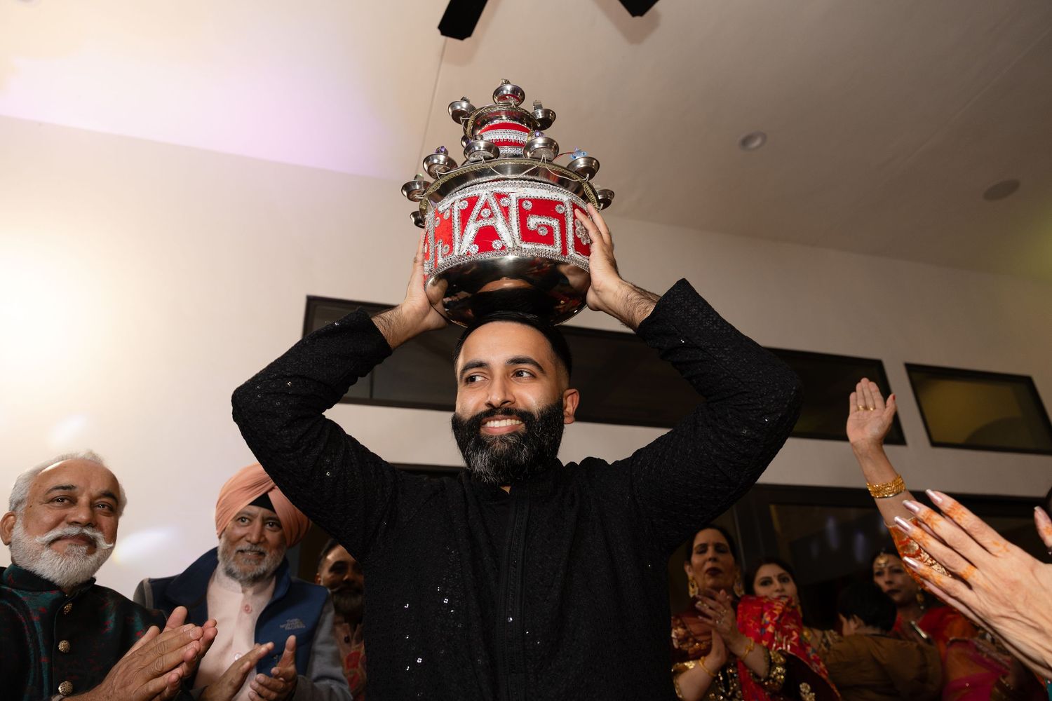People celebrating with raised arms and joyful expressions during what appears to be a festive indoor gathering.