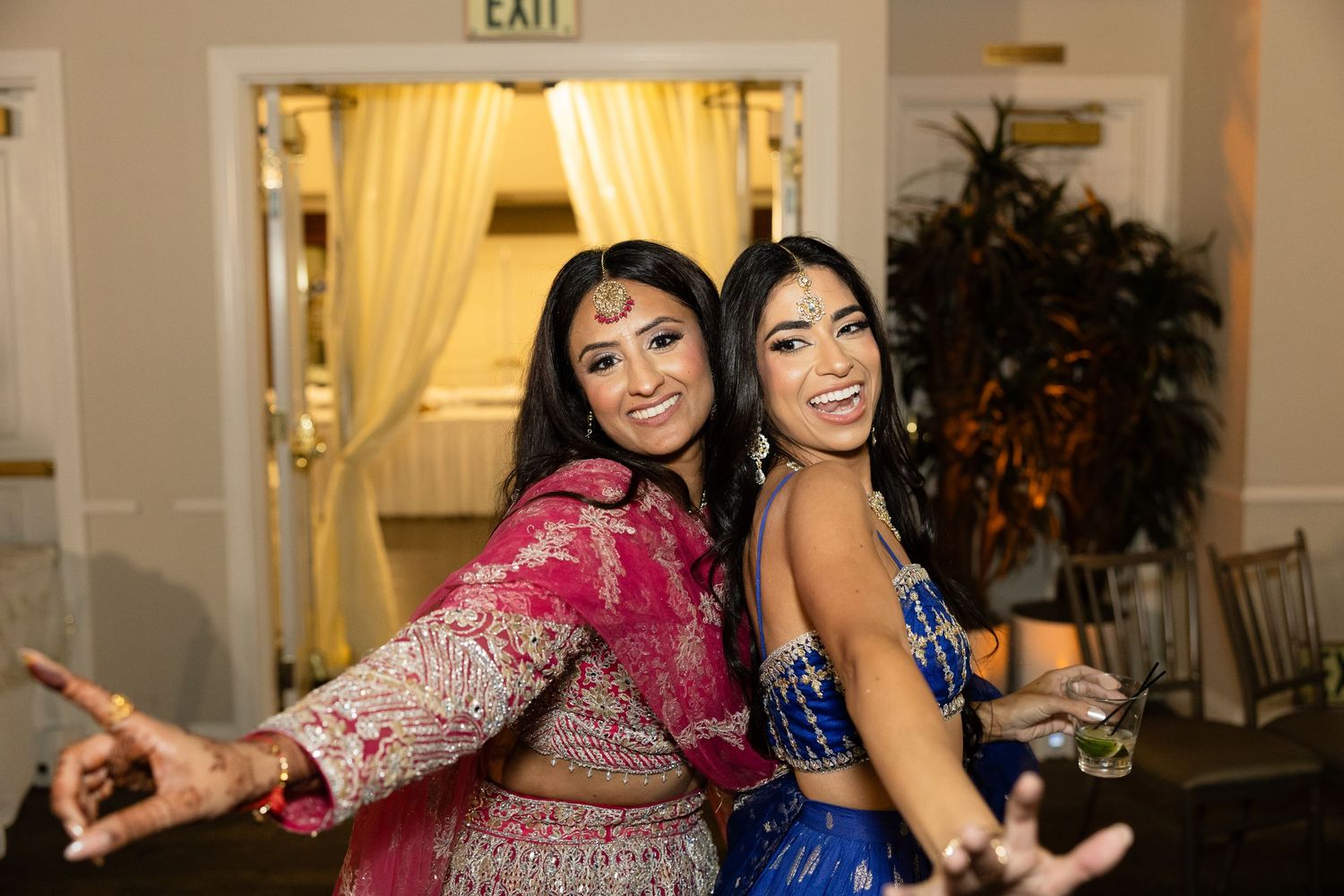 People dancing and celebrating at an elegant indoor wedding reception with white drapes and decorations.