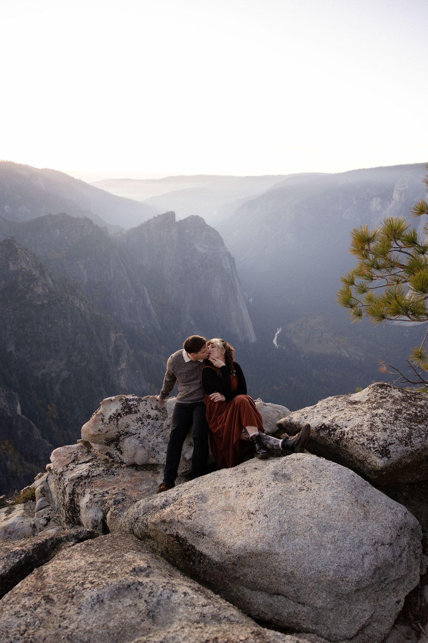 Couple lounging on granite rocks with expansive Yosemite Valley views in late afternoon light.