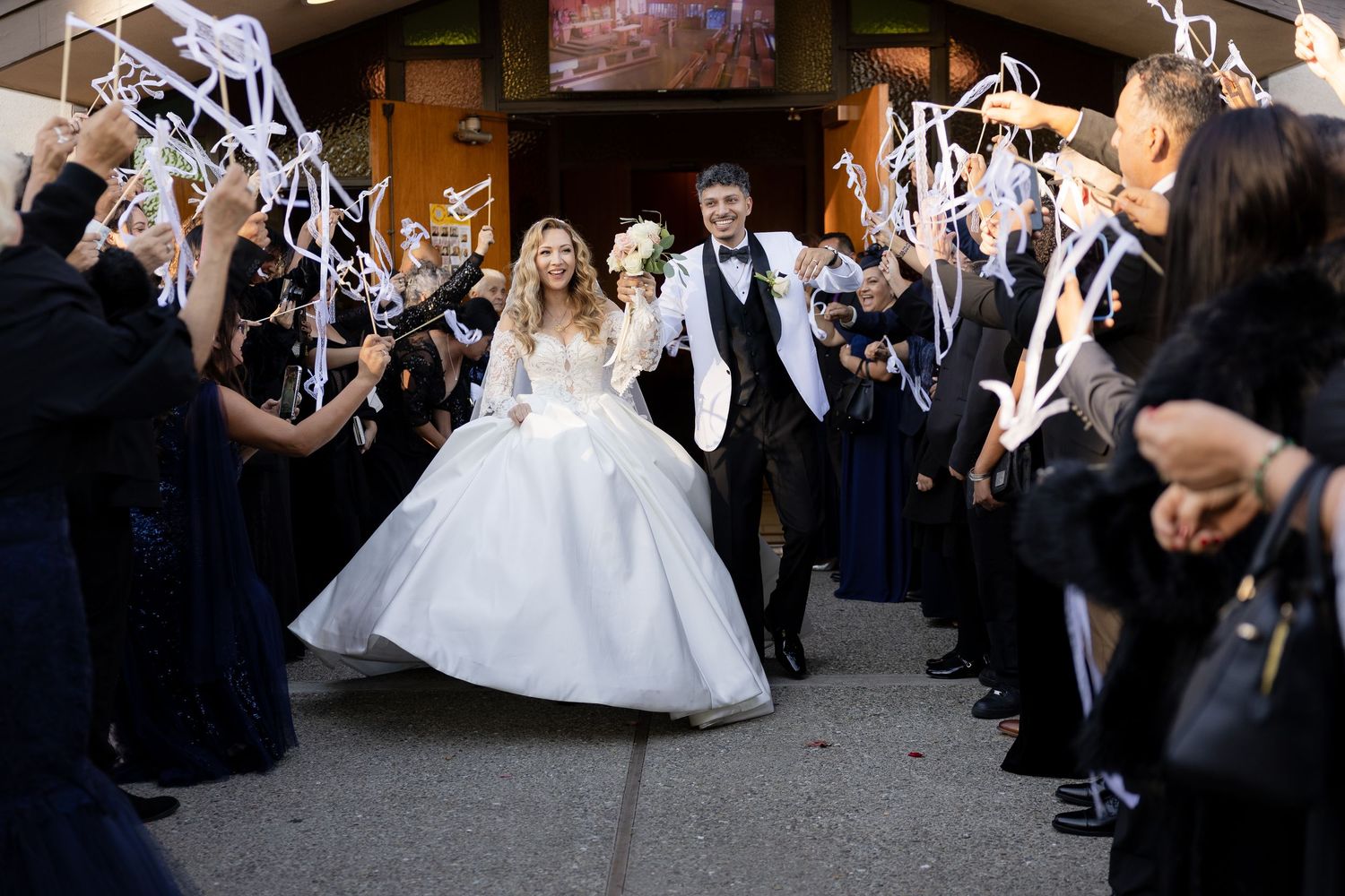Wedding party forms a sparkler tunnel indoors as guests celebrate the special moment.