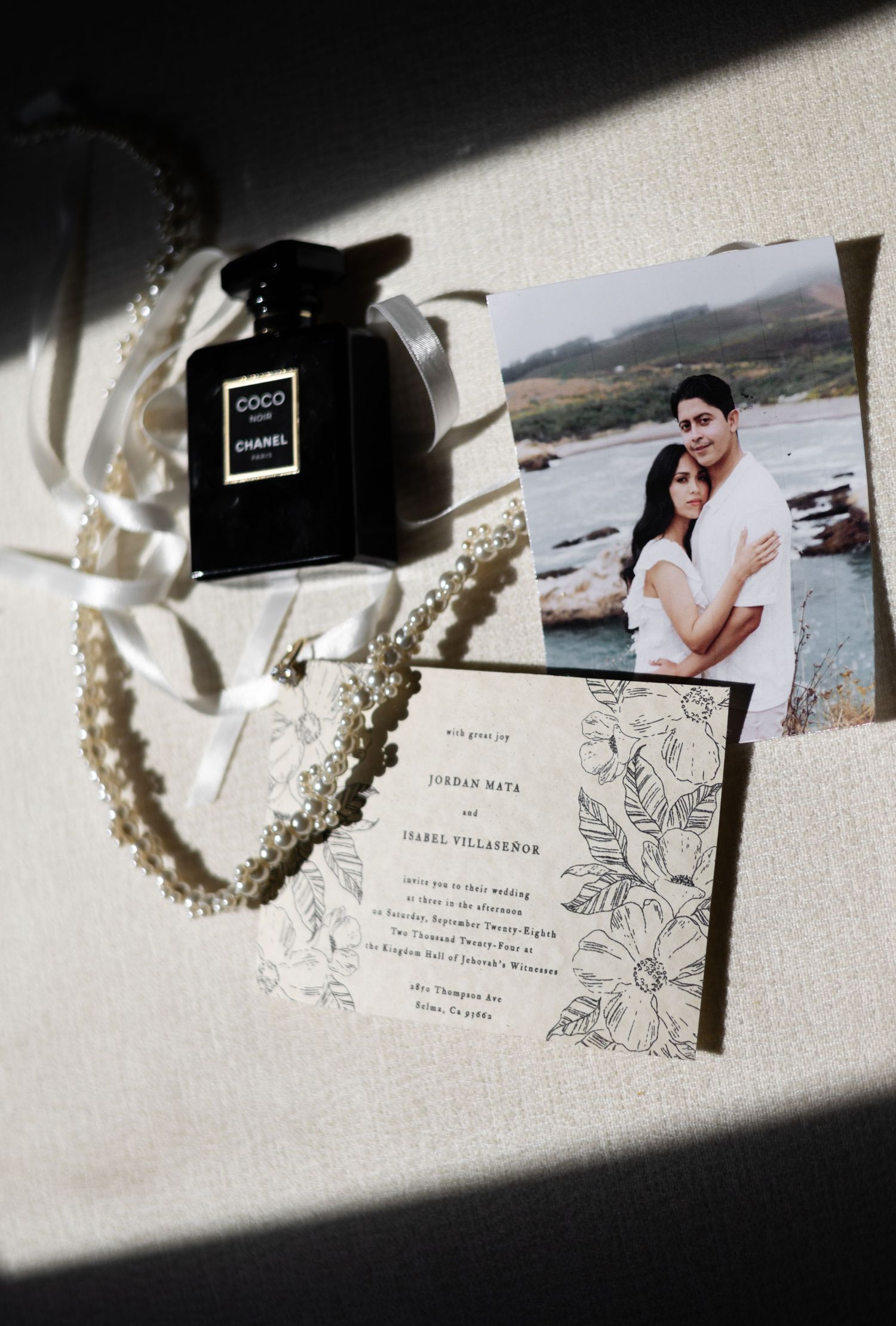 Wedding stationery and pearl necklace displayed with photographs in natural light.