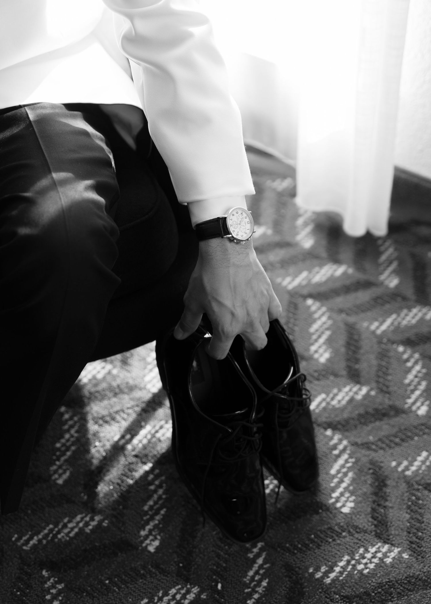 Close-up views of hands tying formal black dress shoes on textured flooring.