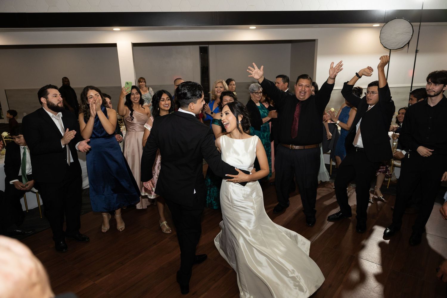 Wedding guests dancing and celebrating in a spacious reception venue.