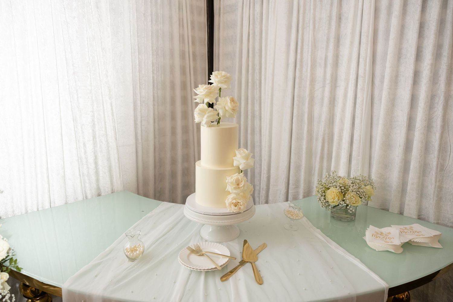 Wedding reception venue setup with elegant white draping and floral centerpieces.