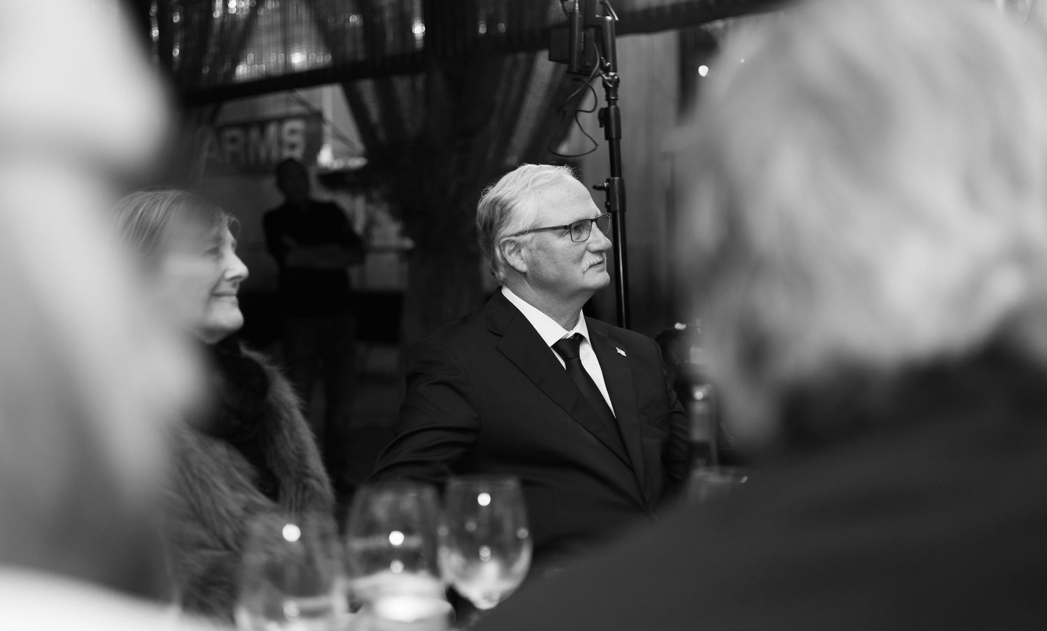 Black and white candid shots of wedding guests during reception speeches.