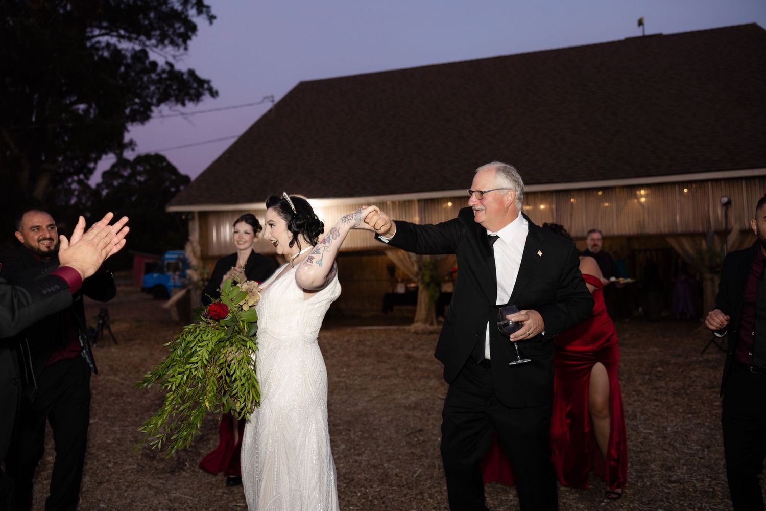 Wedding celebration under string lights at dusk with guests dancing.