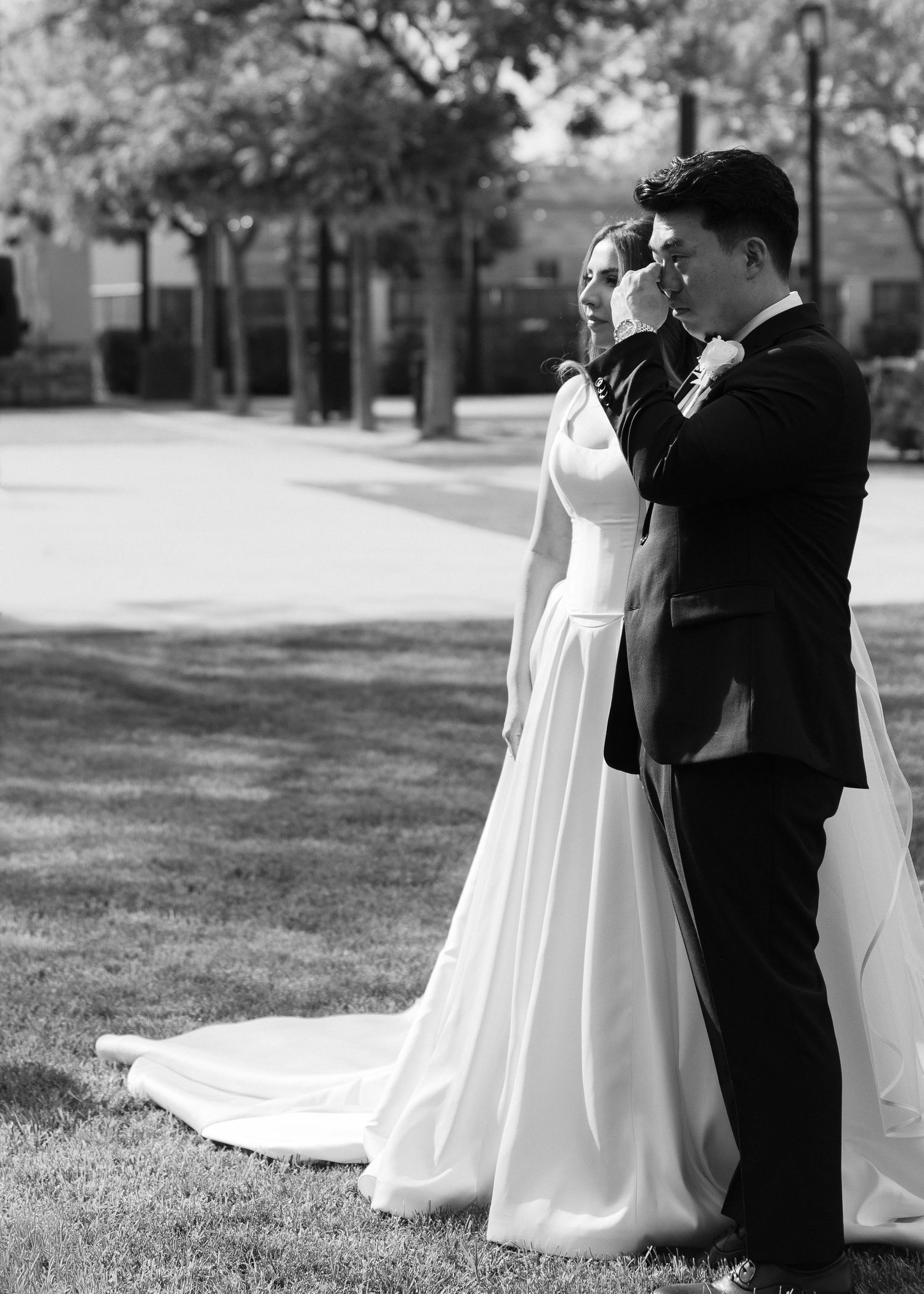 Groom tenderly kisses brides hand during emotional first look moment in black and white.