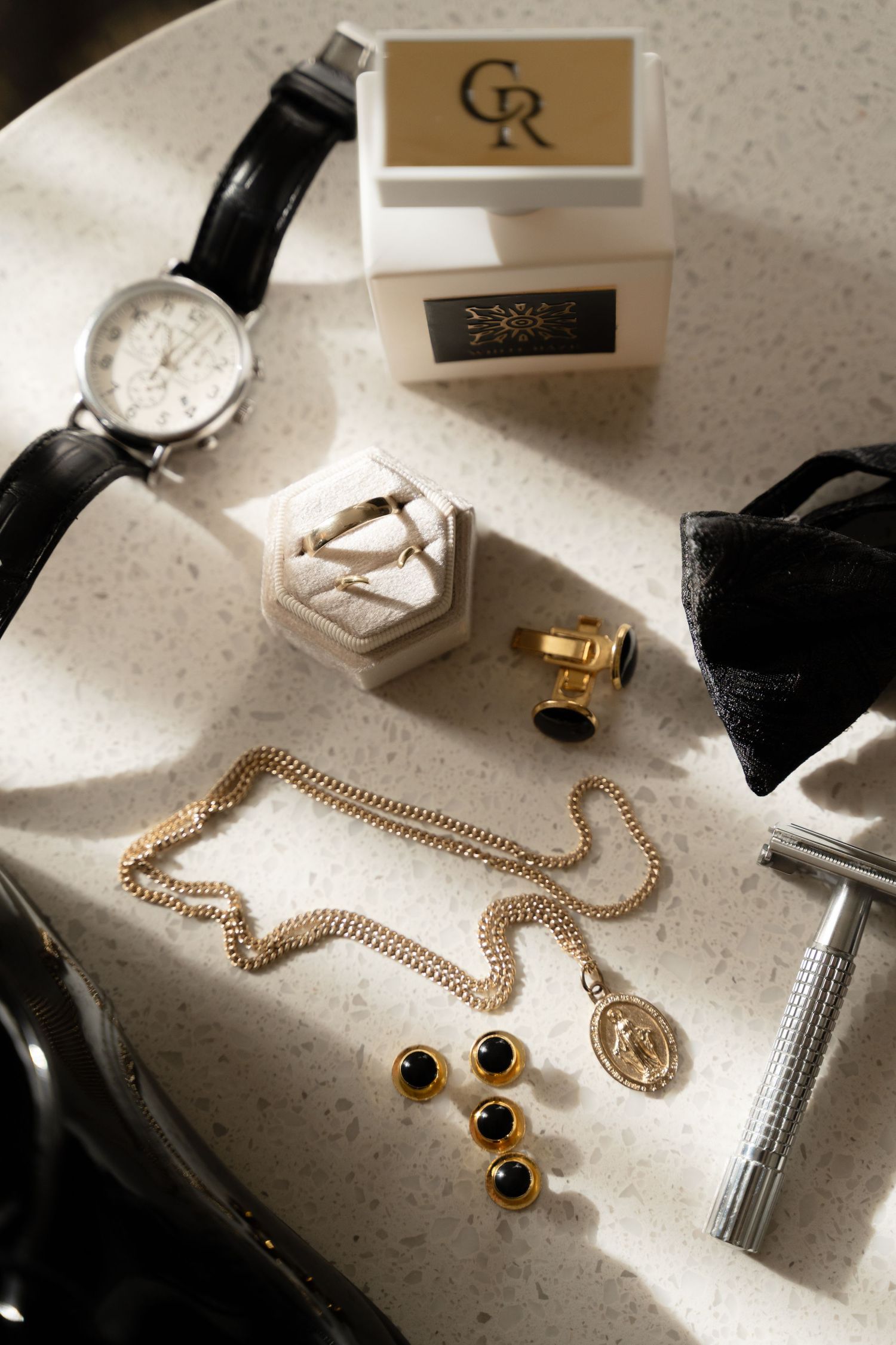 Gold jewelry and accessories arranged on a light colored surface with elegant packaging.