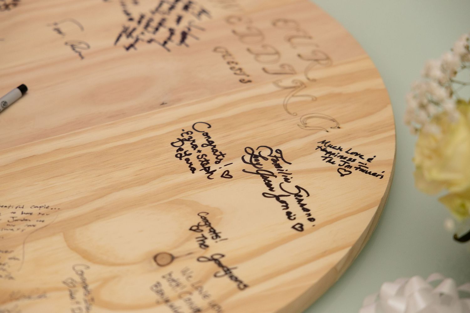 Close-up of wooden wedding guestbook with handwritten messages and signatures.