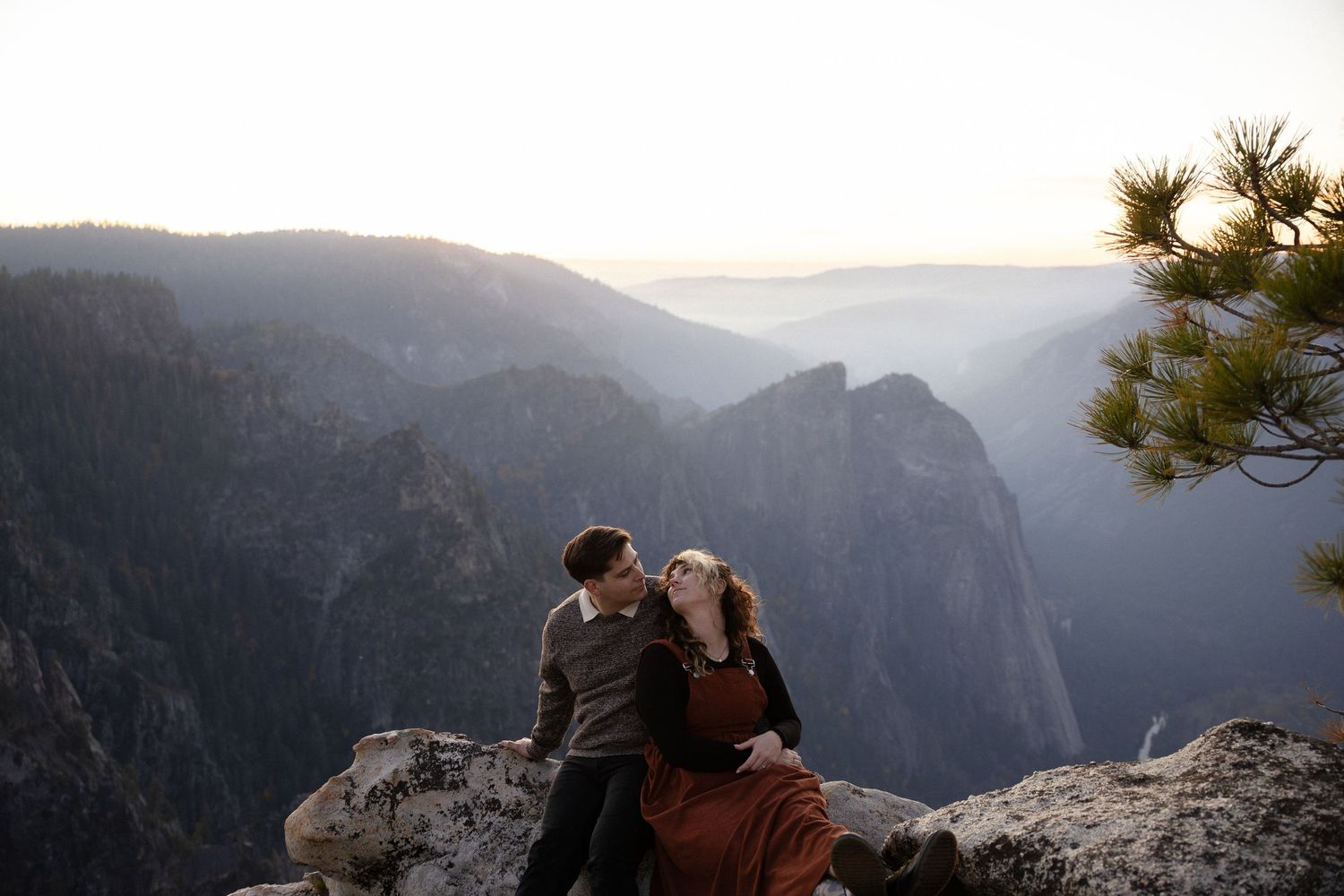 A romantic moment captured on a cliff edge with dramatic mountain vistas in the background.