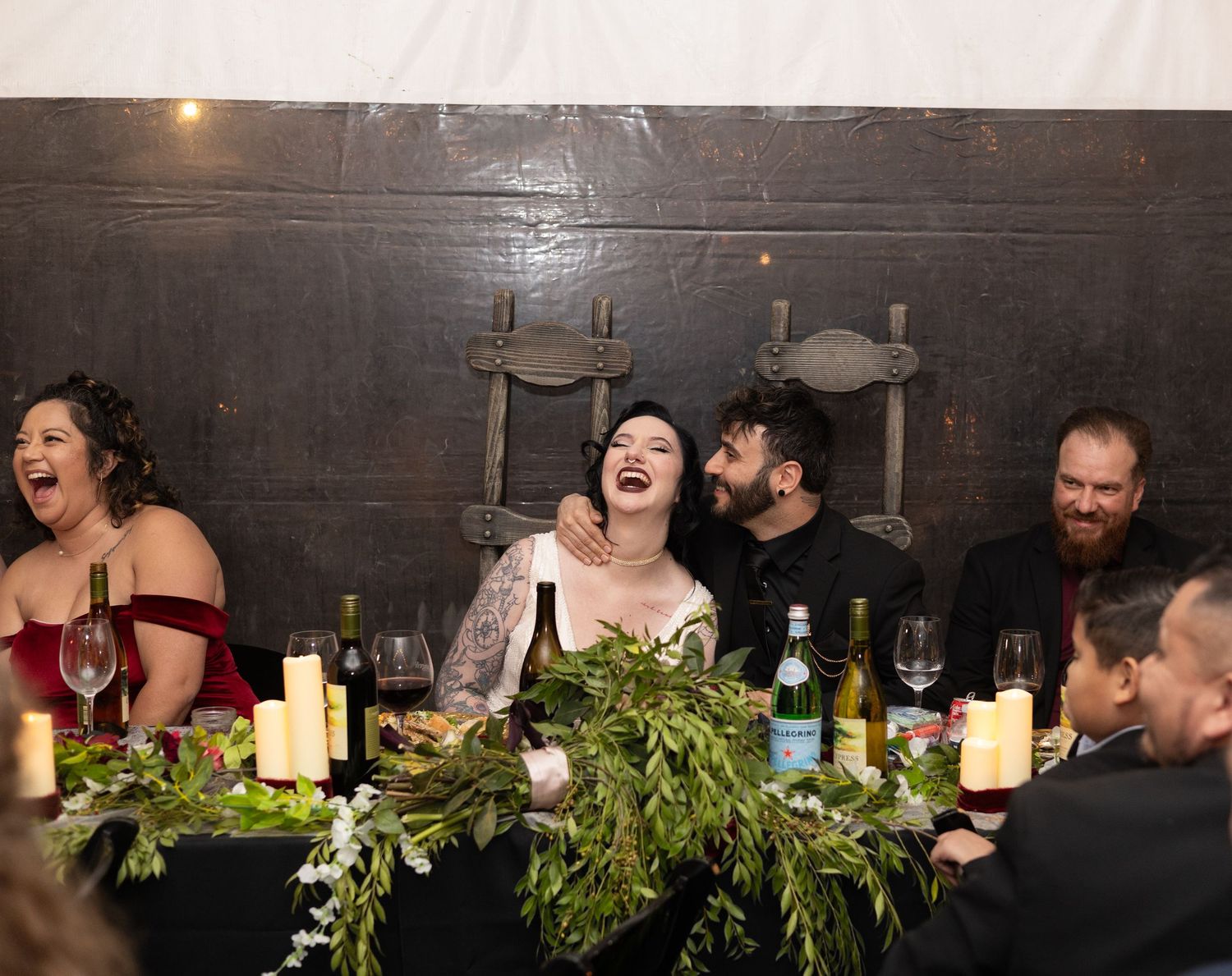 Long dining table decorated with greenery and candles at an indoor wedding reception.