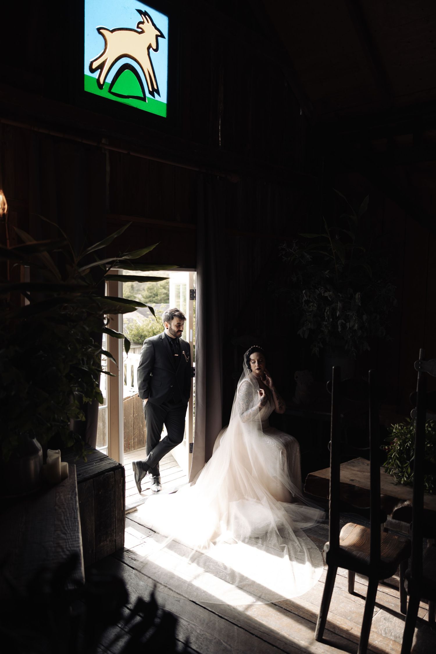 Wedding party silhouetted in doorway with dramatic natural lighting and shadows.