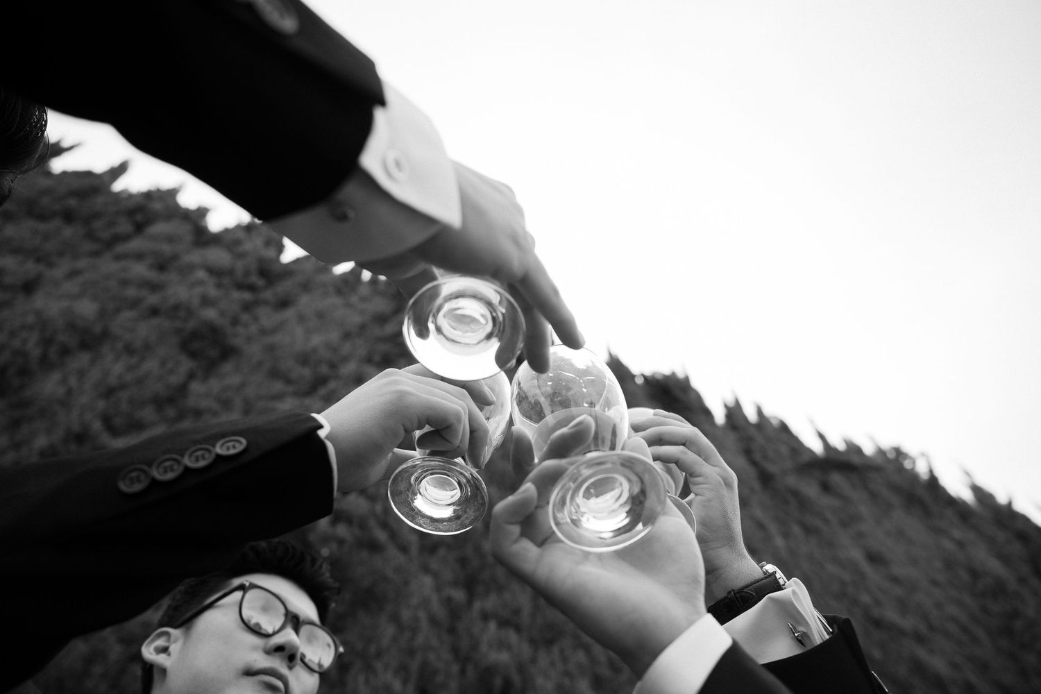 Groomsmen in suits raise glasses in a celebratory toast at a wedding reception.