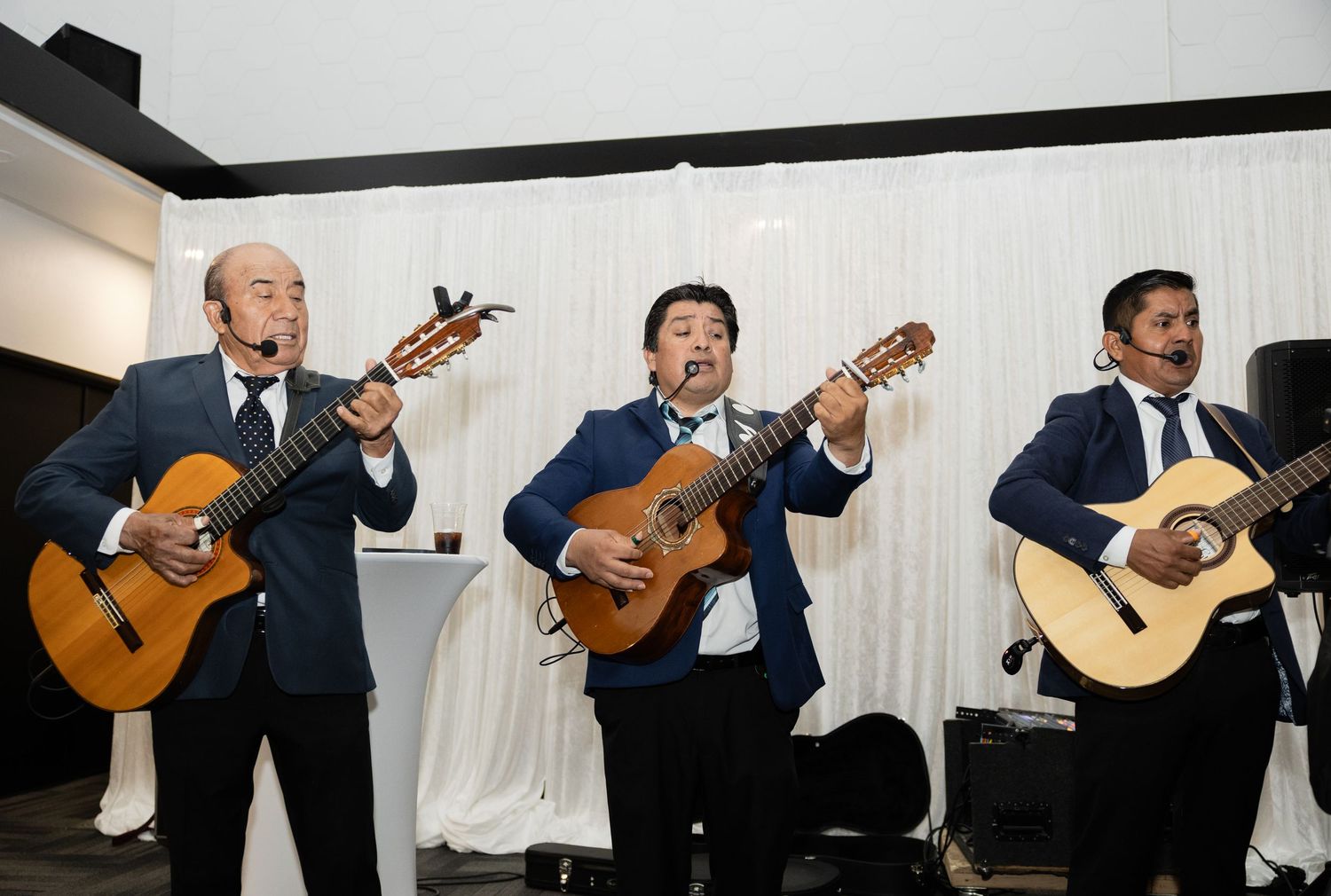 Musicians in formal attire perform with acoustic guitars at an event.
