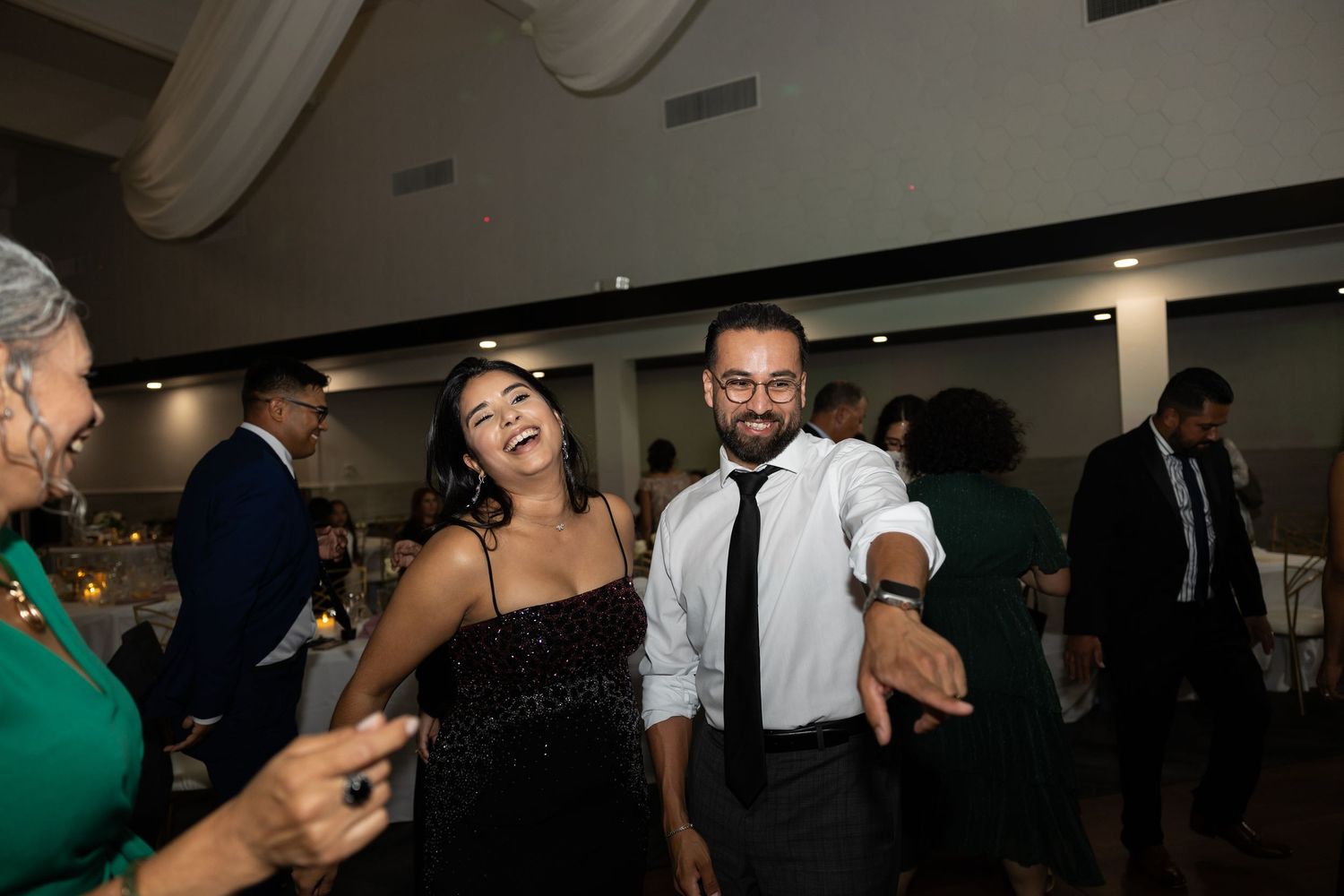 Dimly lit wedding reception venue with guests dancing and celebrating.