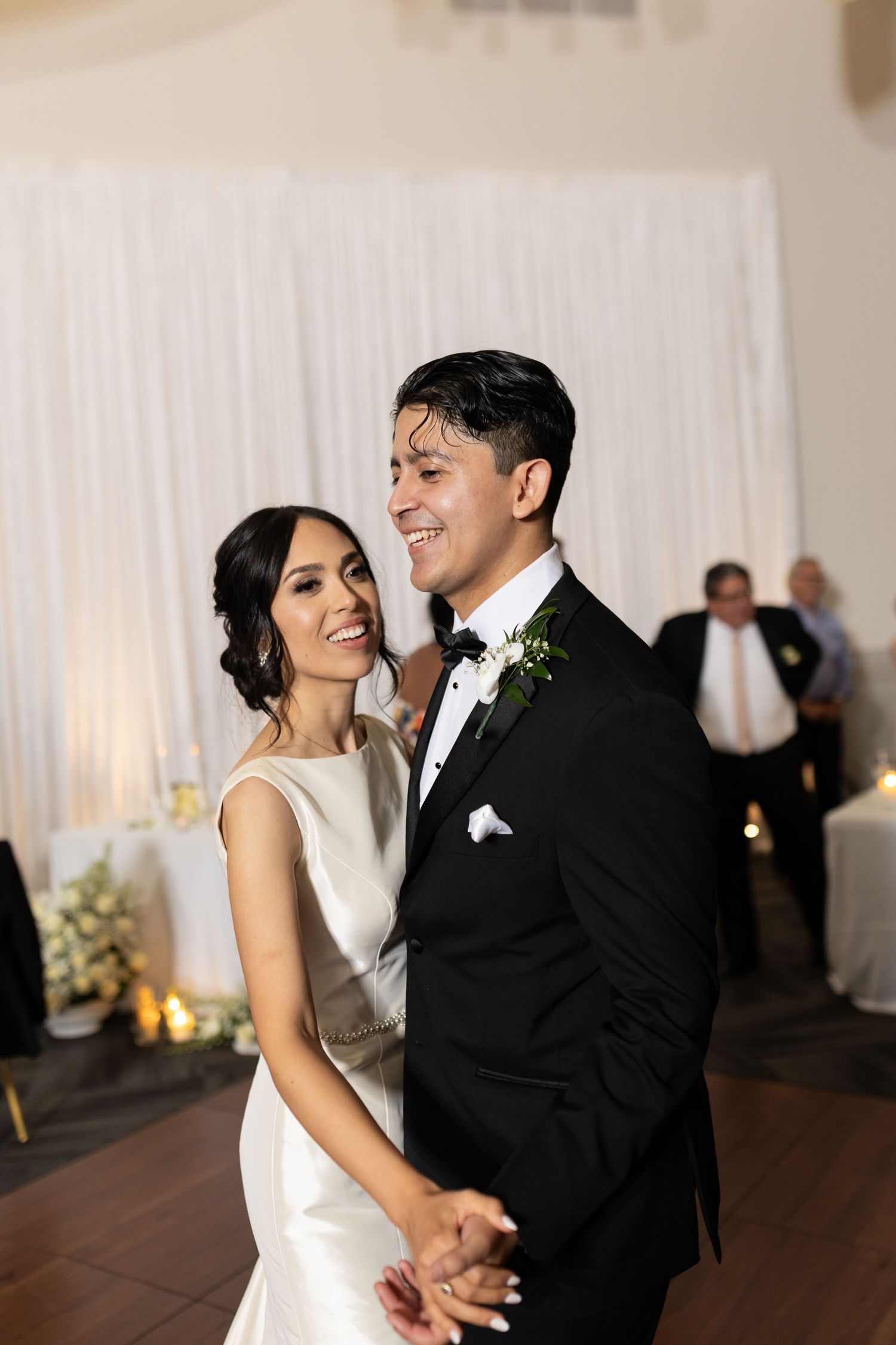 Newlyweds laugh joyfully while dancing together at their wedding reception.