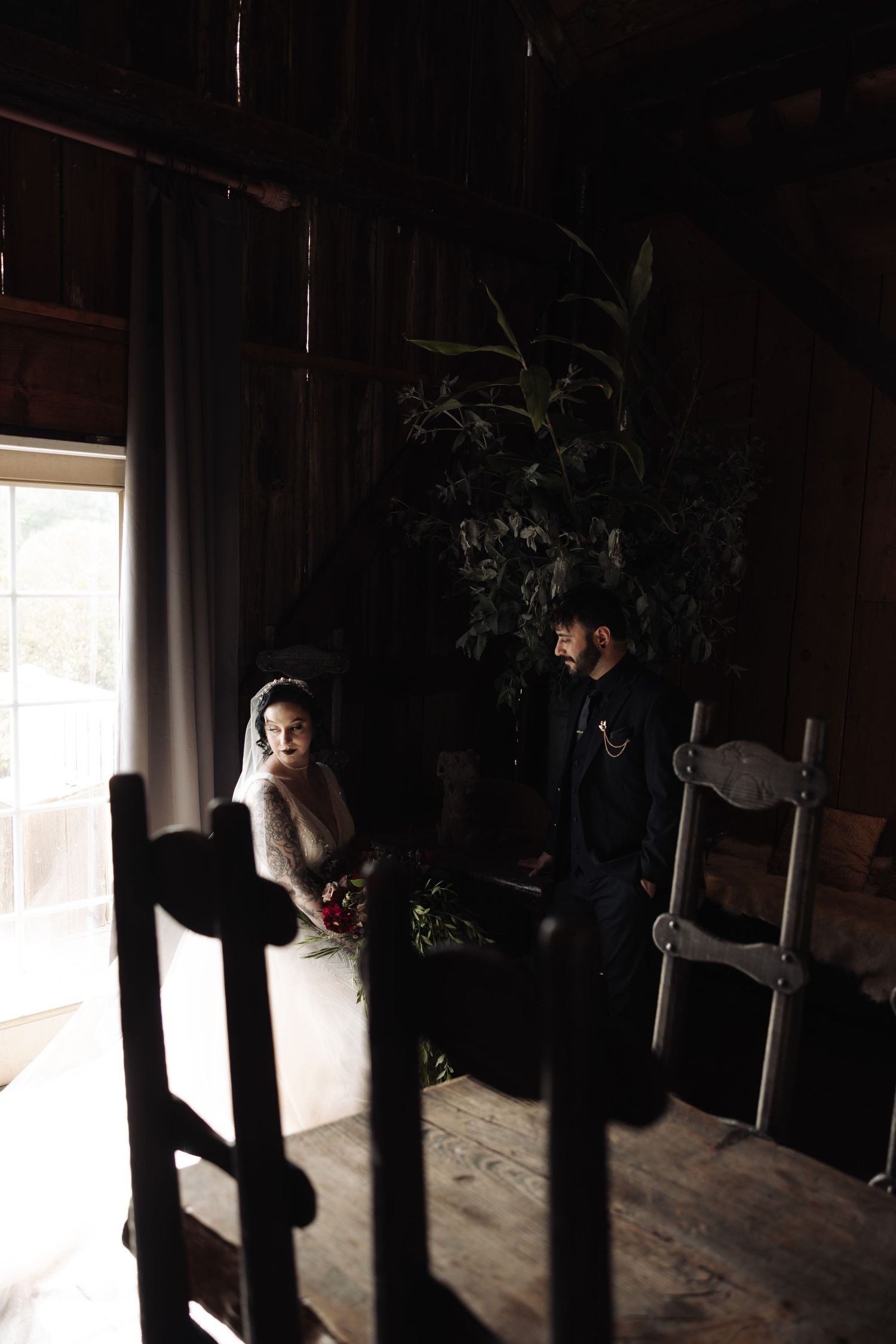 Dark interior of barn with dramatic window lighting and shadows.