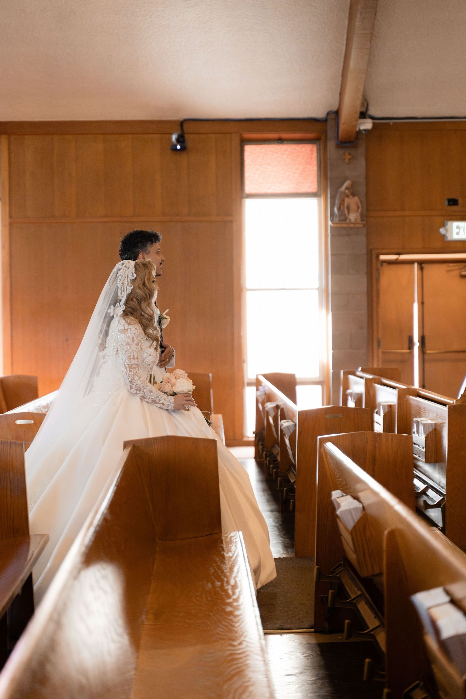 Sepia-toned photo of bride in wedding dress walking through church pews.
