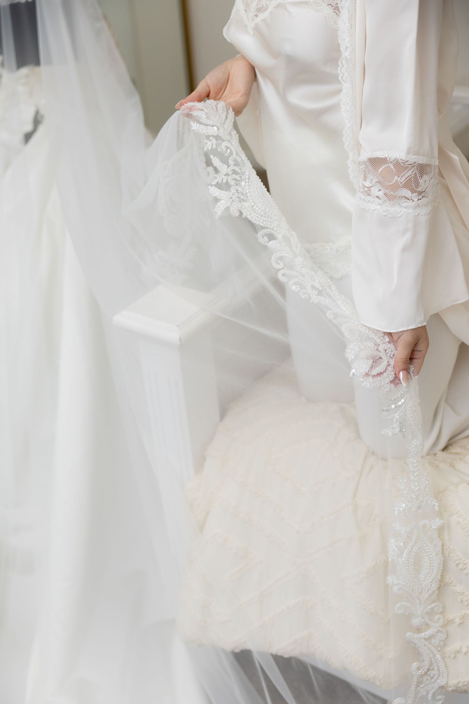 Close-up details of delicate white lace and fabric on a wedding dress.