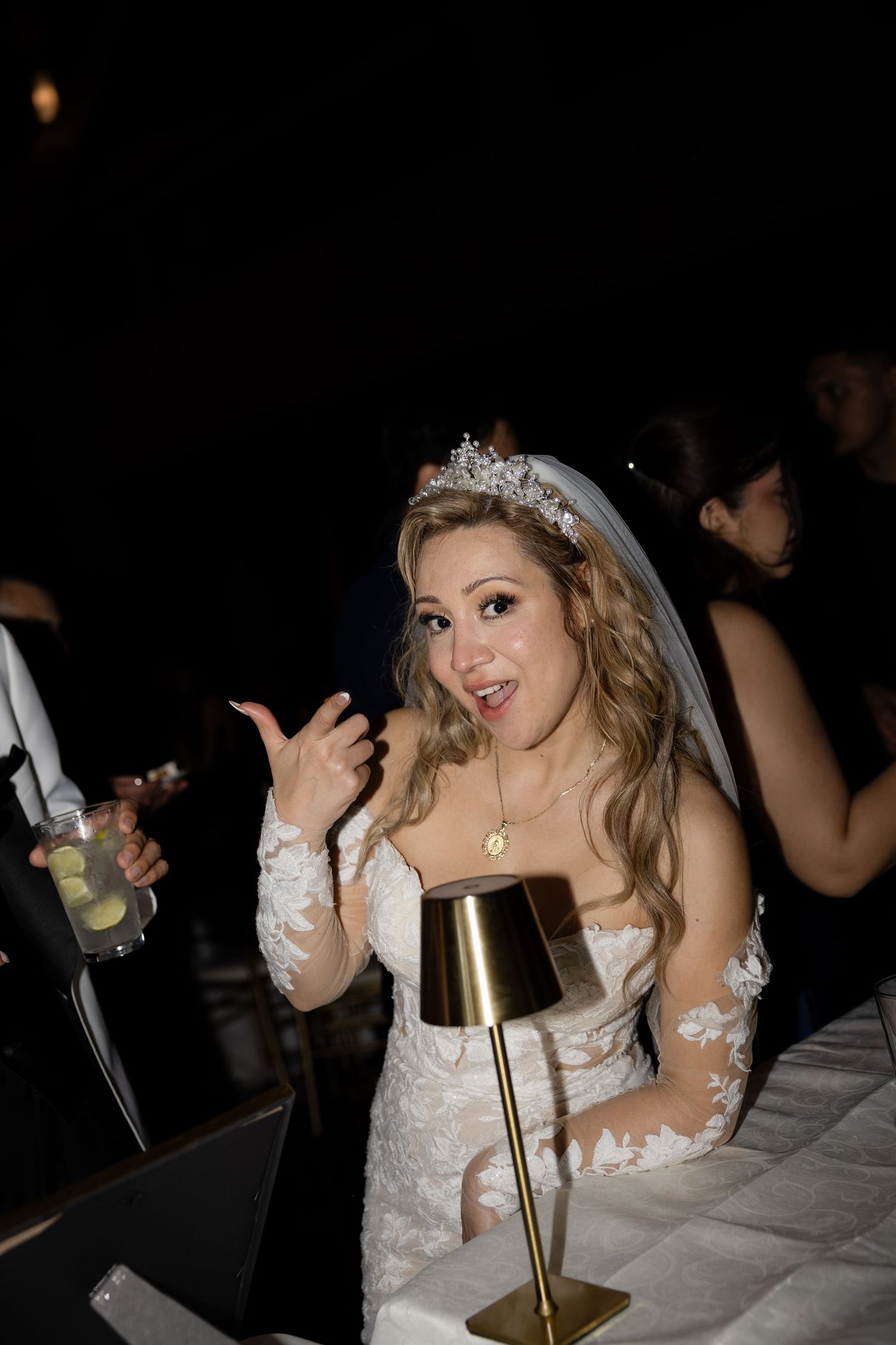 Bride in lace dress enjoying reception festivities with animated expressions.