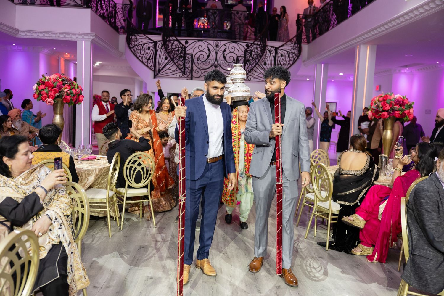 Wedding guests dancing and celebrating on a purple-lit dance floor during an elegant reception party.