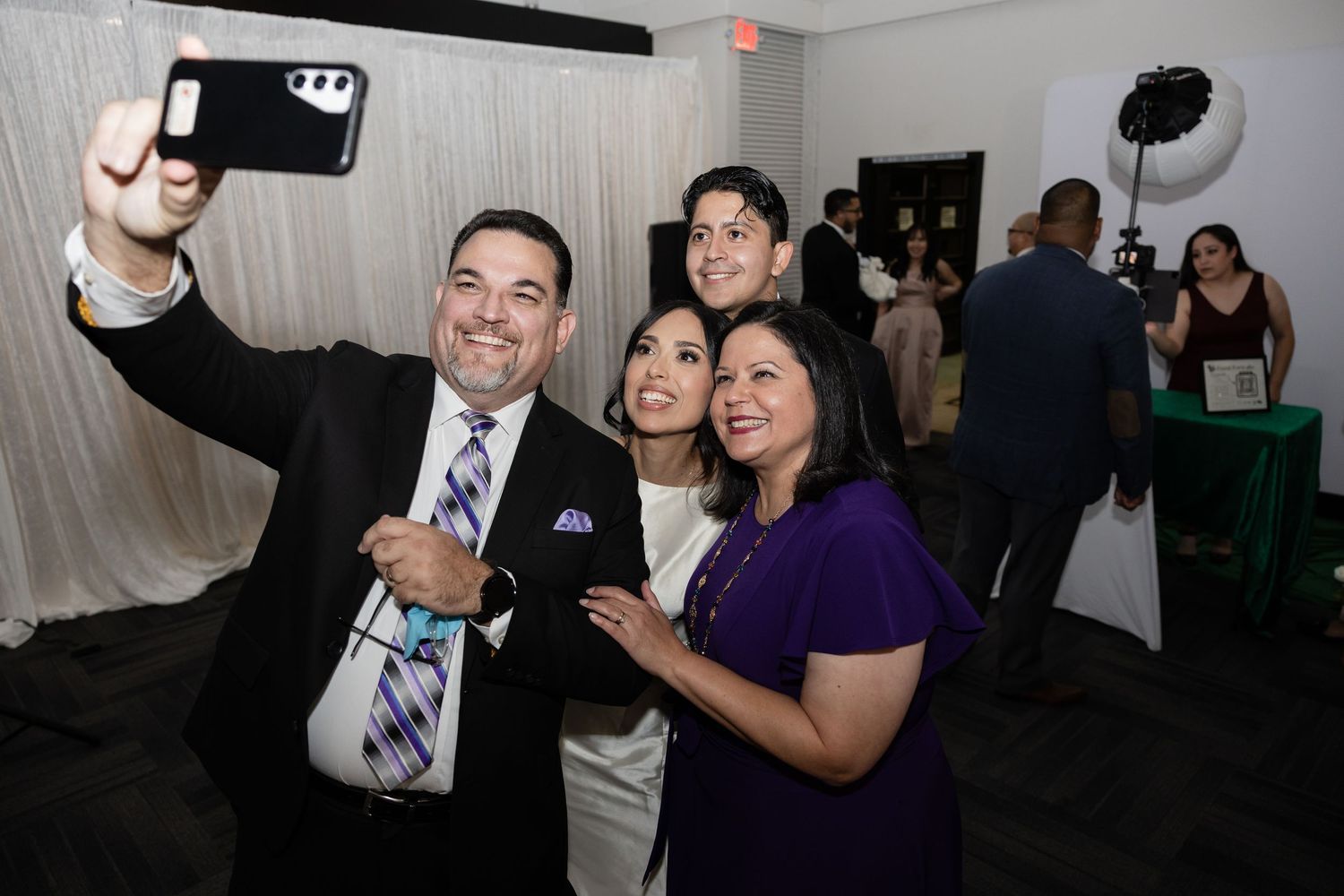 Guests sharing joyful moments and dancing at a dimly lit wedding reception venue.