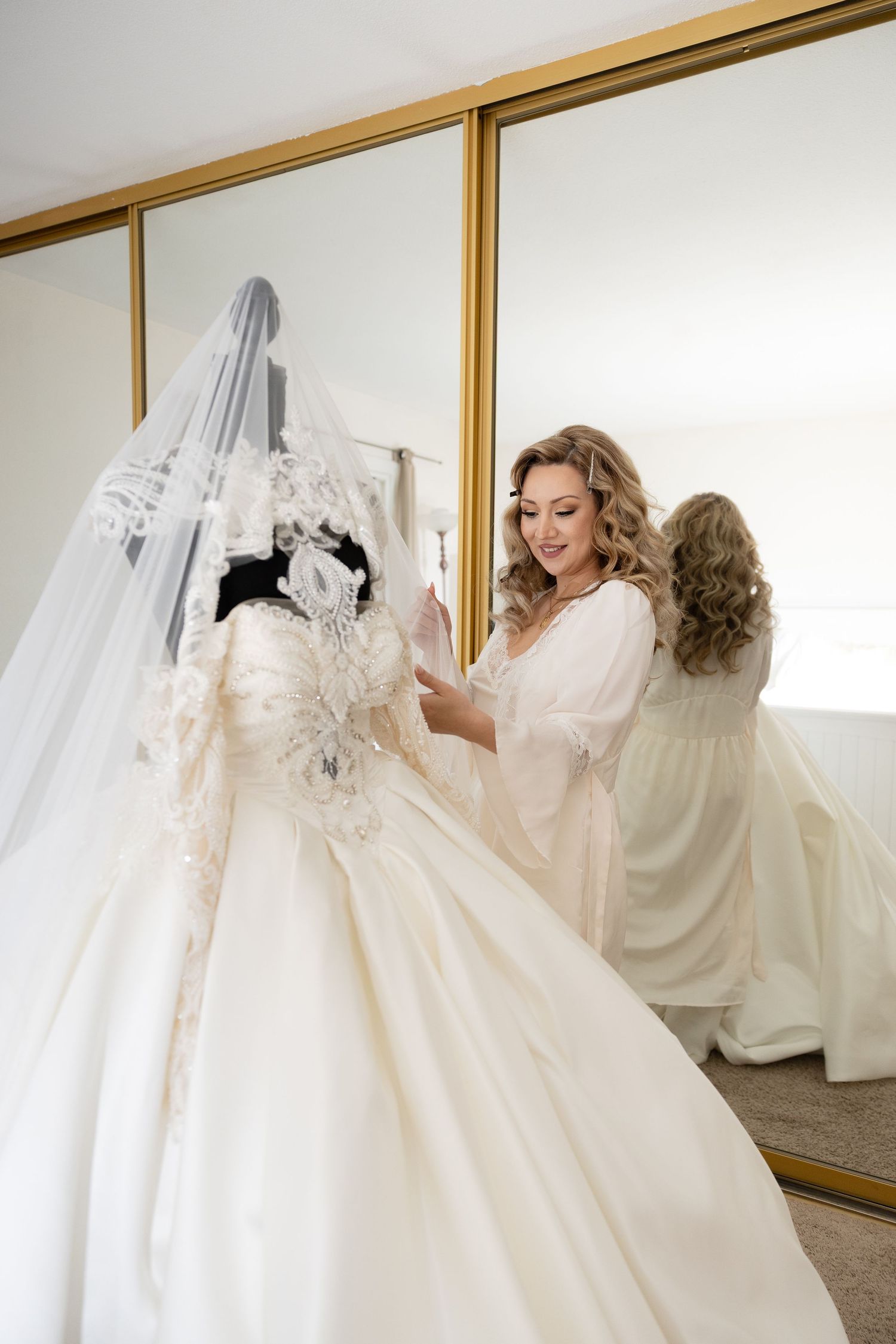 Elegant wedding dress with lace details reflected in a gold-framed mirror.