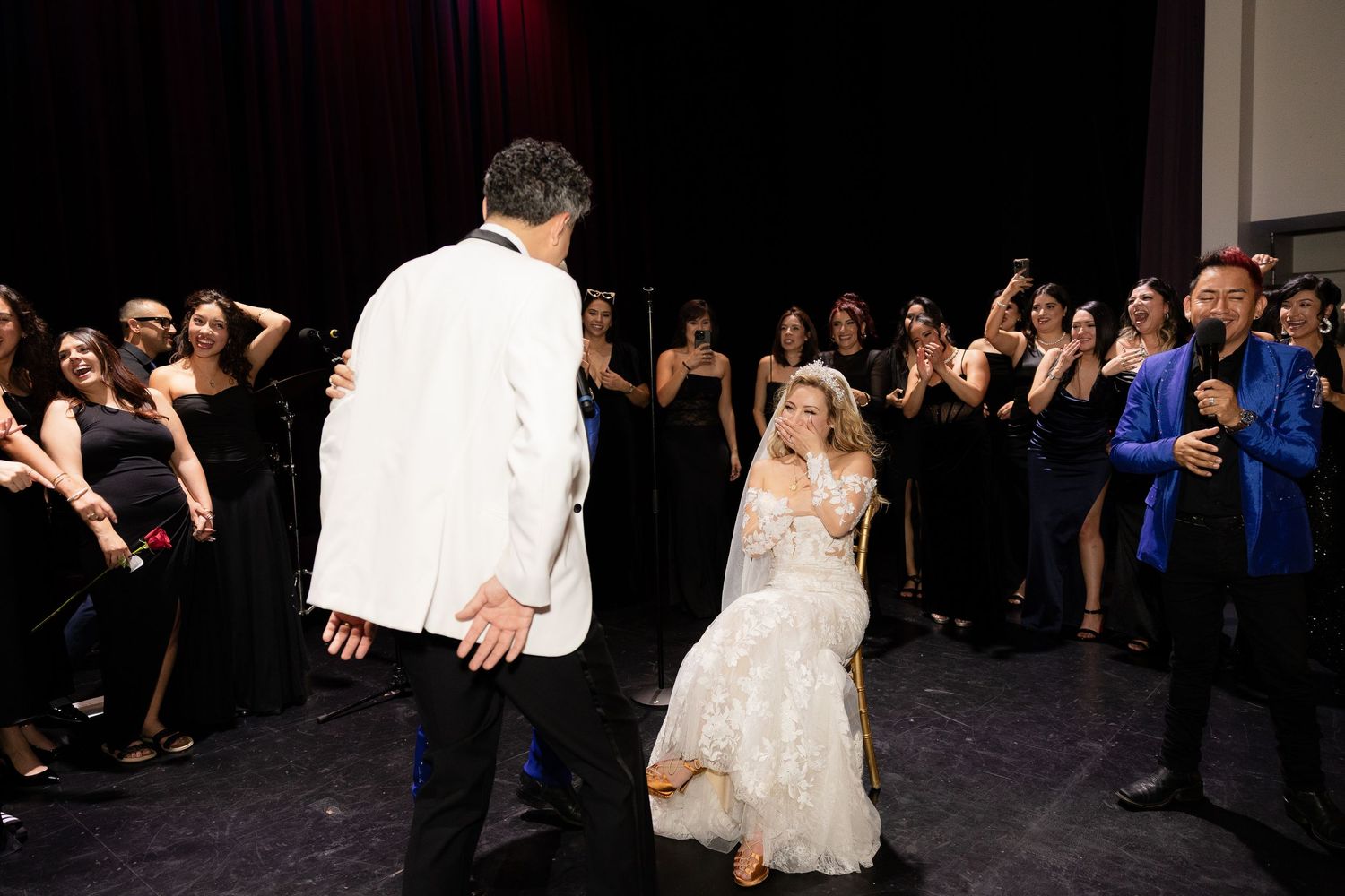 Wedding guests cheer and celebrate while watching a dance performance at the reception.