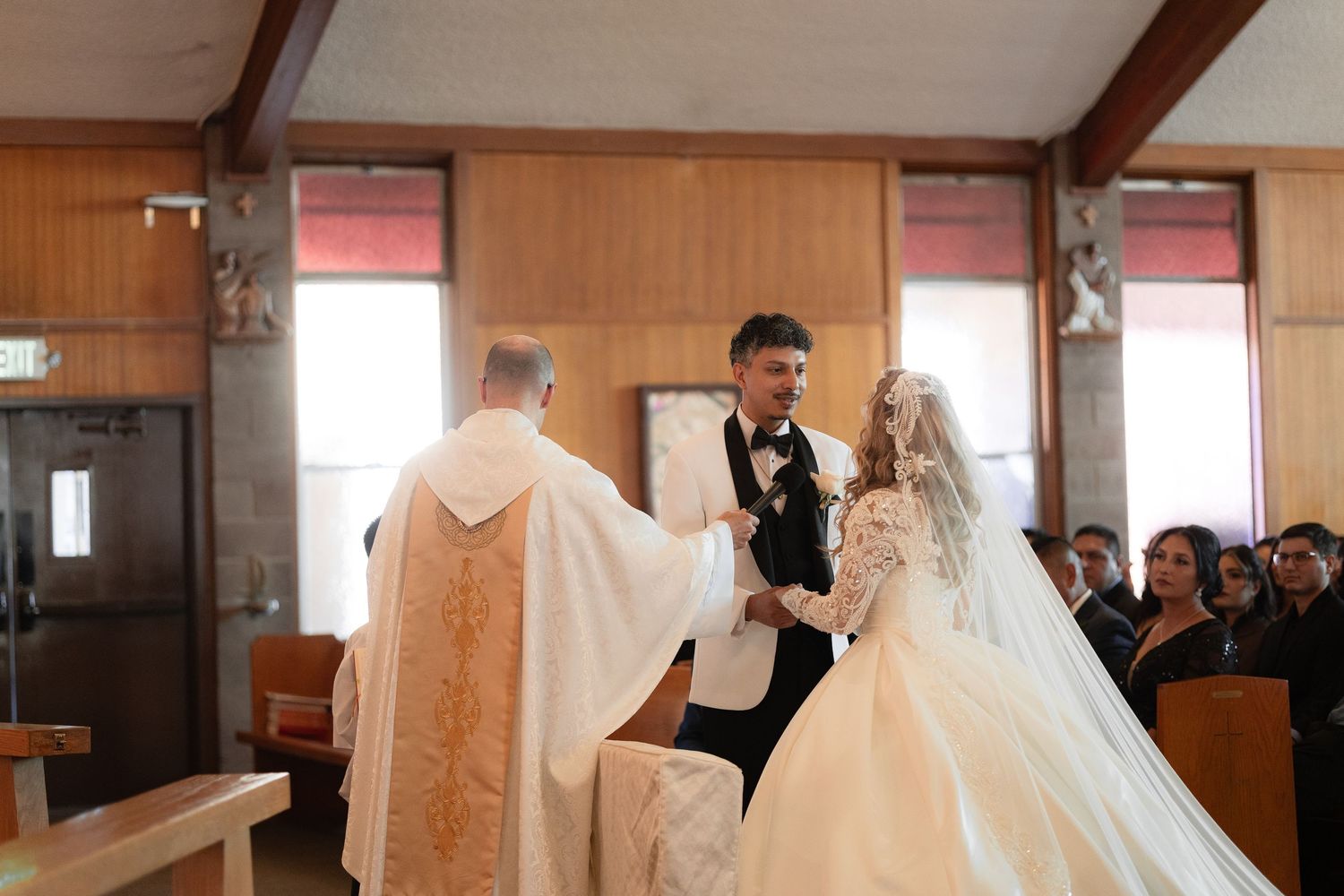 Wedding ceremony taking place in a traditional church setting with wooden walls and pews.