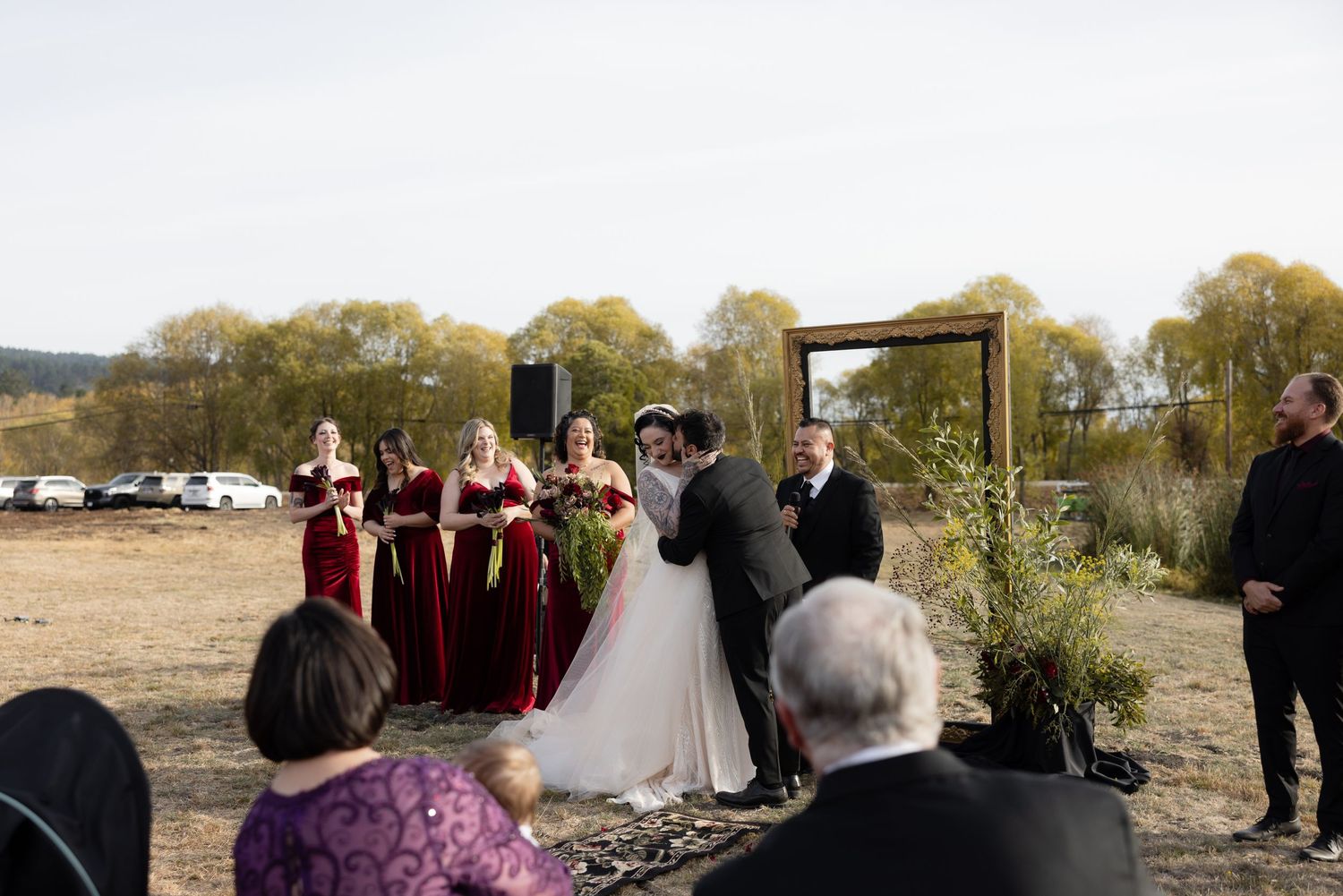 Wedding ceremony in progress with burgundy-clad bridesmaids and guests in attendance.