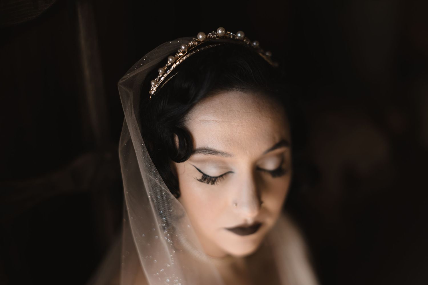 Dramatic bridal portrait with soft side lighting highlighting classic makeup and veil.