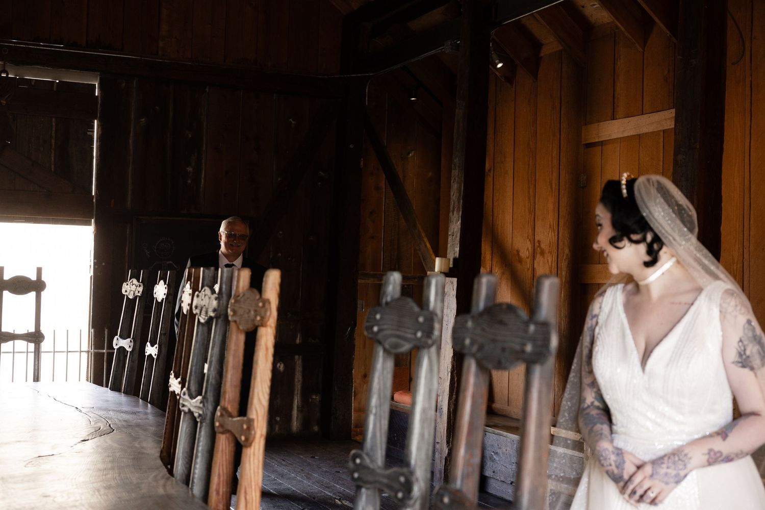 An intimate wedding moment captured in a rustic barn venue with warm wooden interior.
