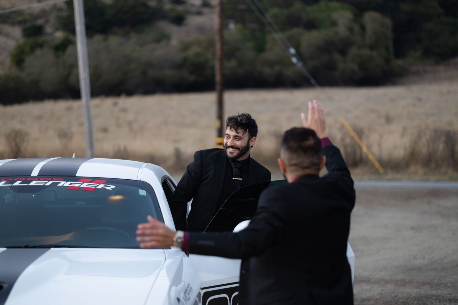 Wedding guests celebrate with raised hands at an outdoor reception.