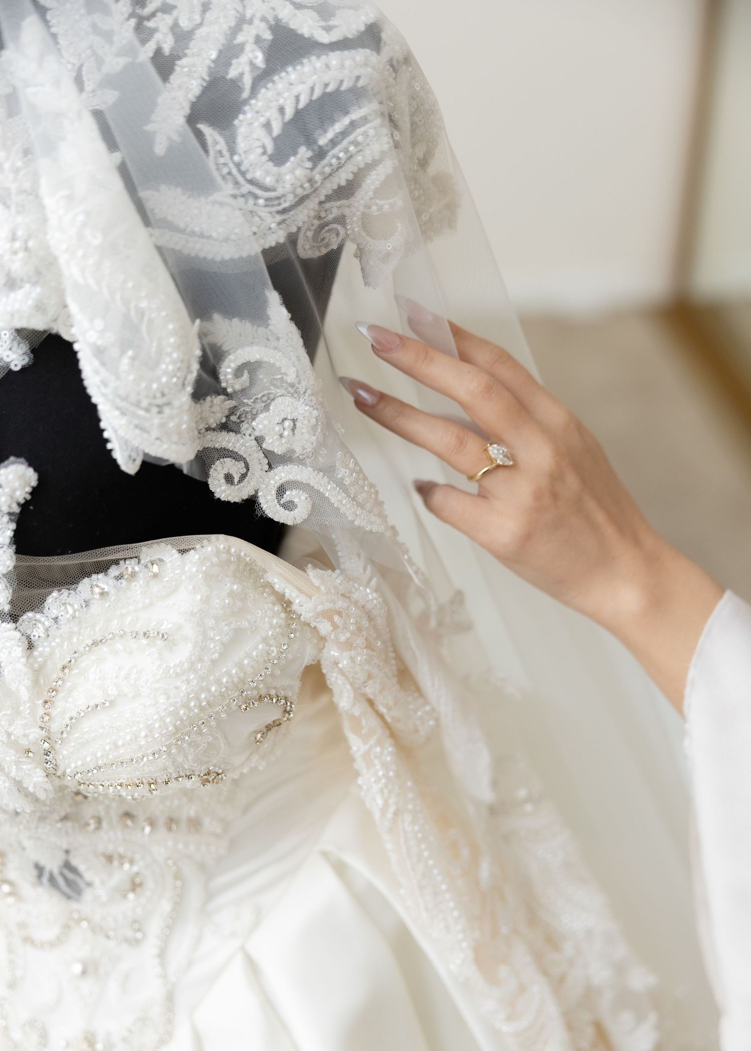 Detailed view of lace embellishments and beading on a white wedding dress.